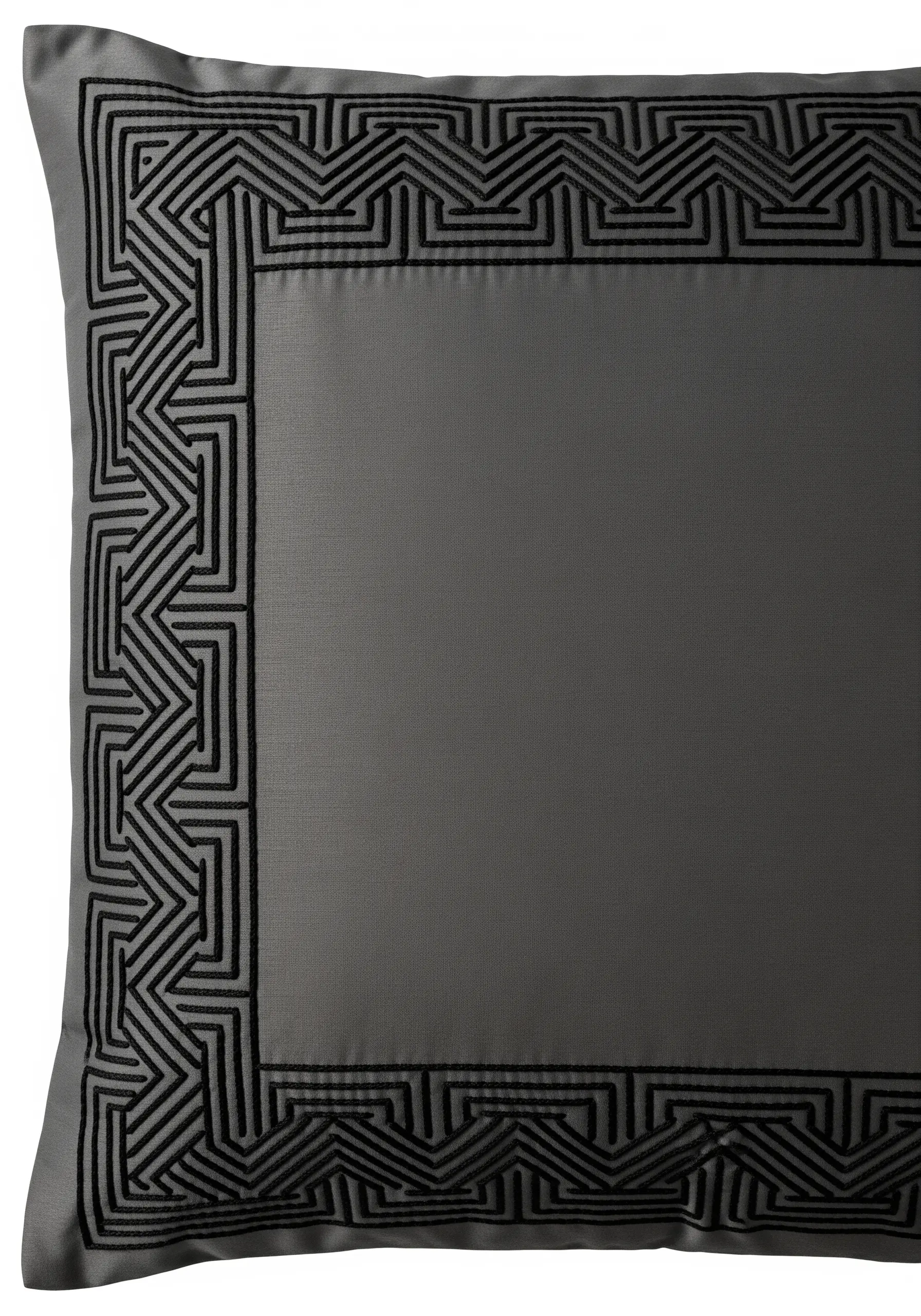 A tone-on-tone geometric maze pattern embroidered in black on a grey cushion