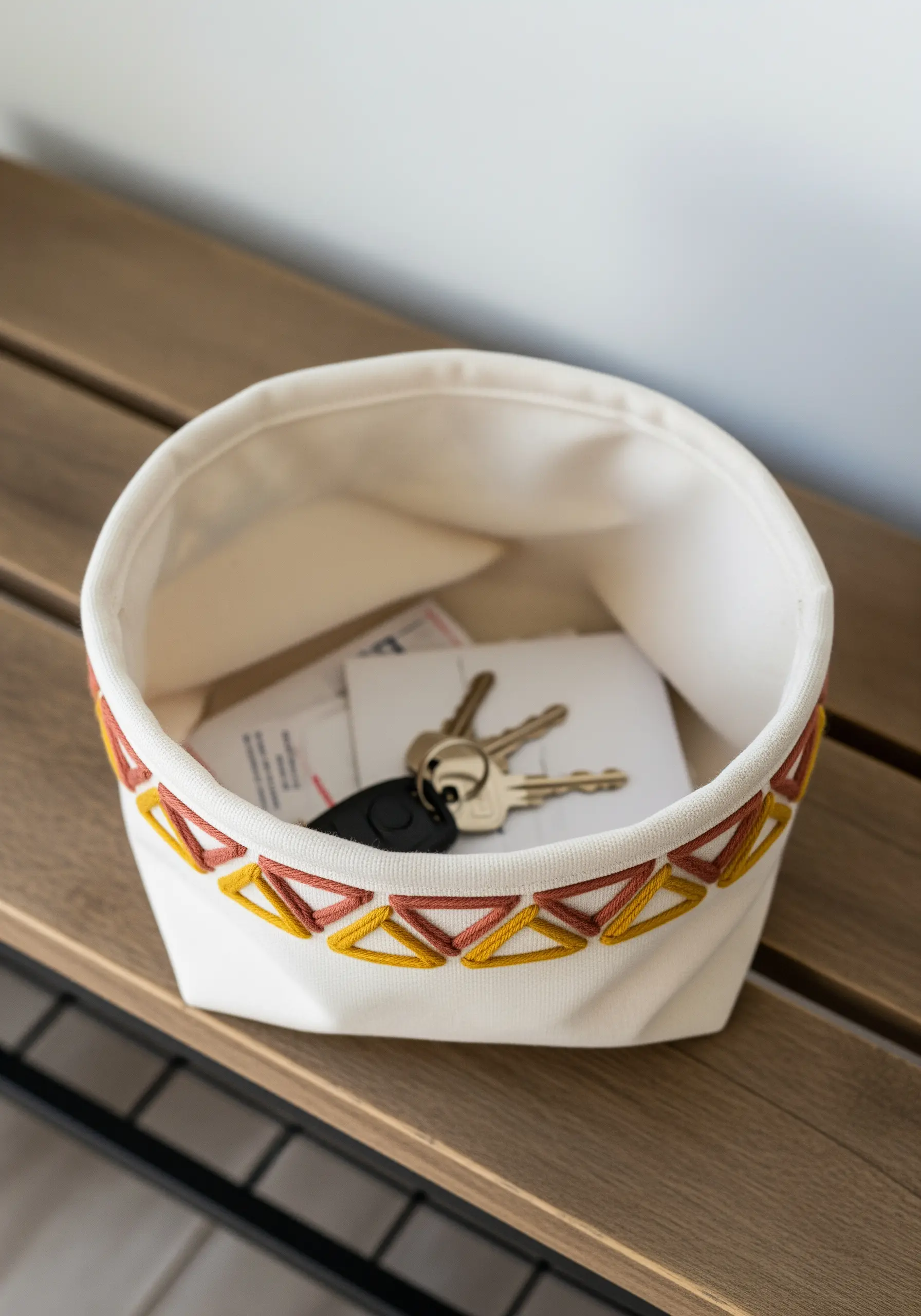 Geometric blanket stitch border in warm tones on the rim of a fabric bowl.