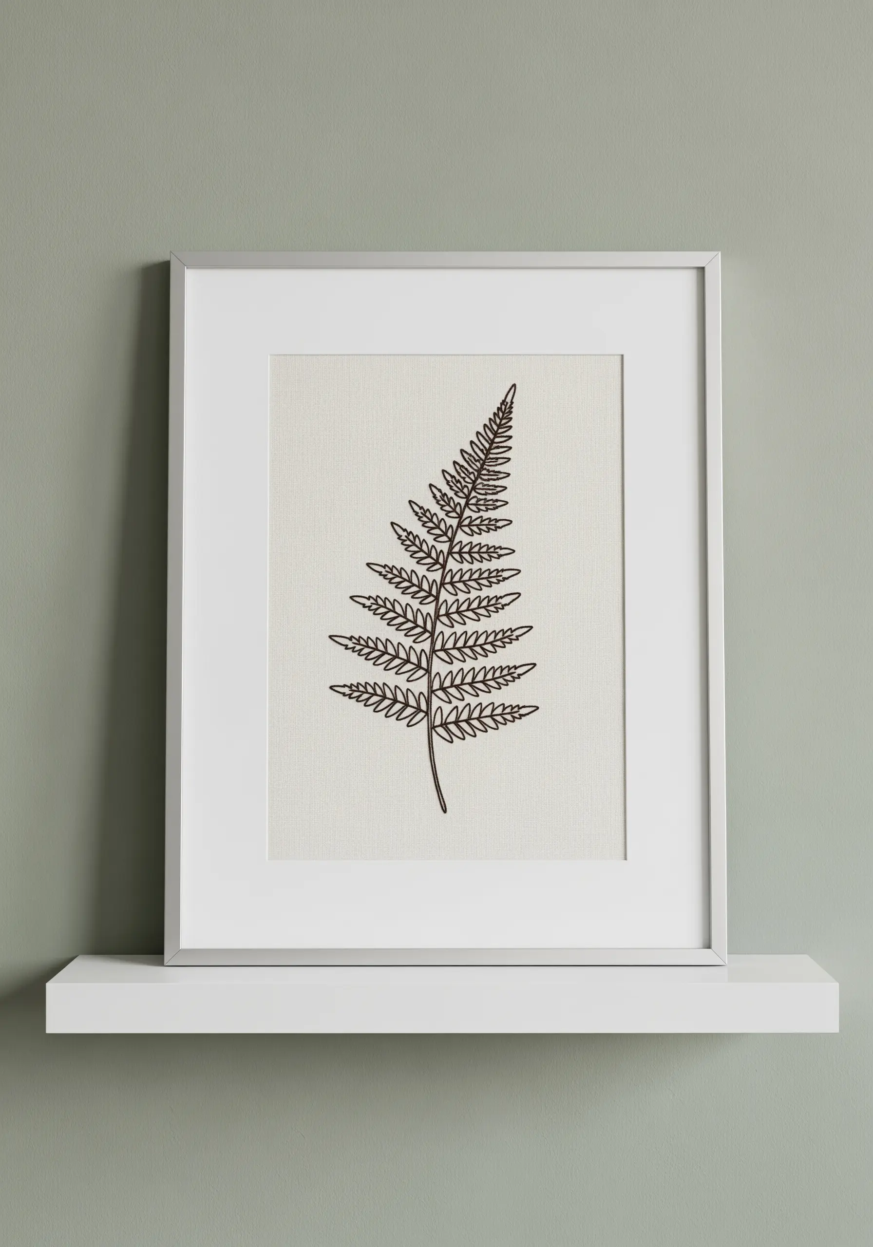 Framed minimalist line art embroidery of a single fern leaf on neutral fabric.