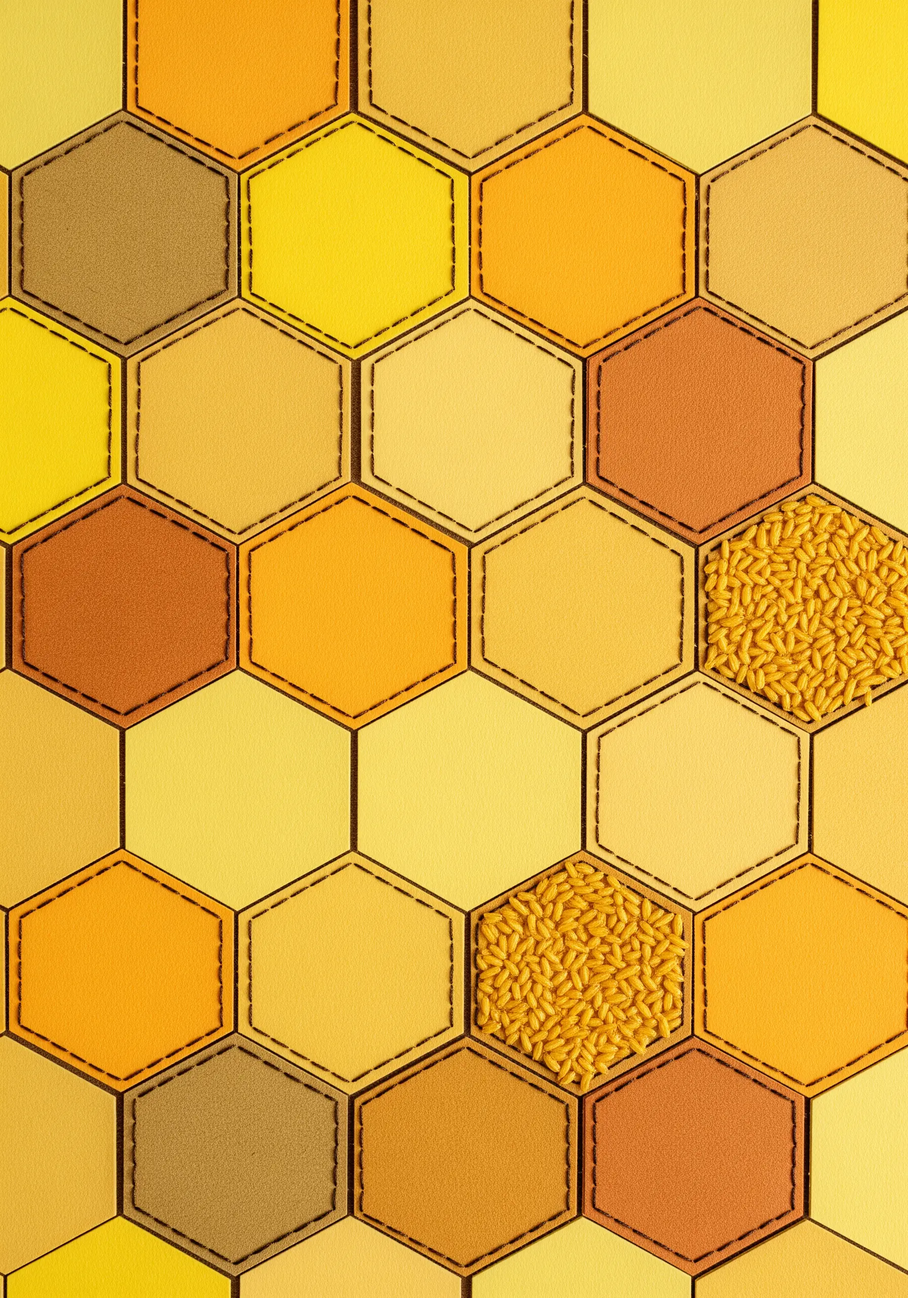 A honeycomb pattern of yellow and orange paper hexagons outlined with thread.