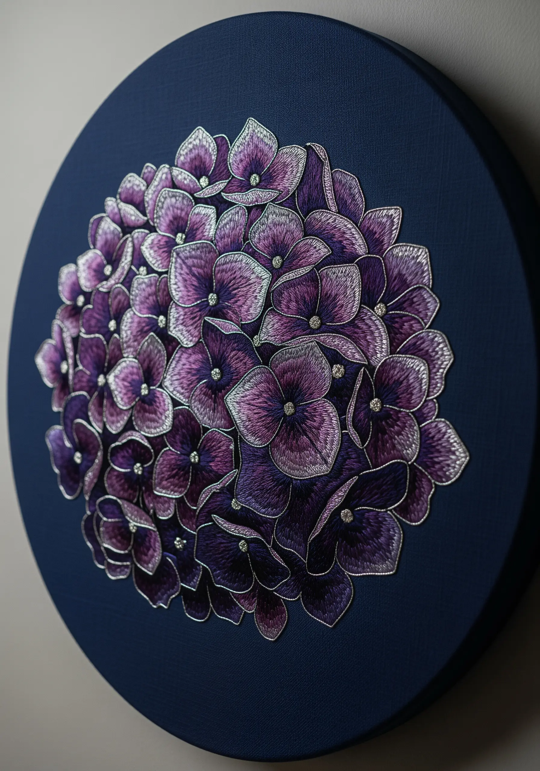 Purple hydrangea on a round navy canvas, with each petal outlined in shimmering silver thread.