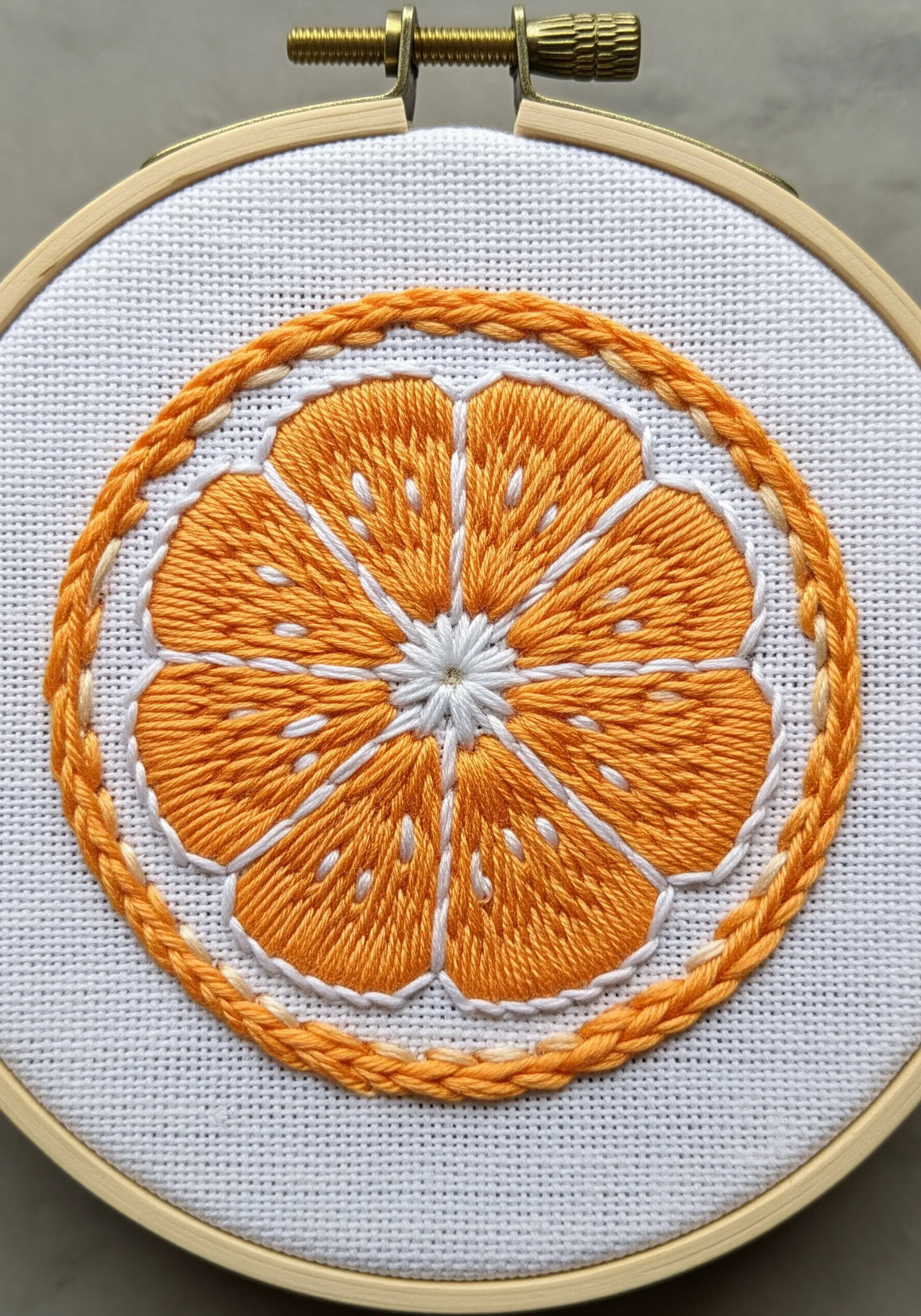 A cleanly embroidered orange slice with defined segments and a braided border.