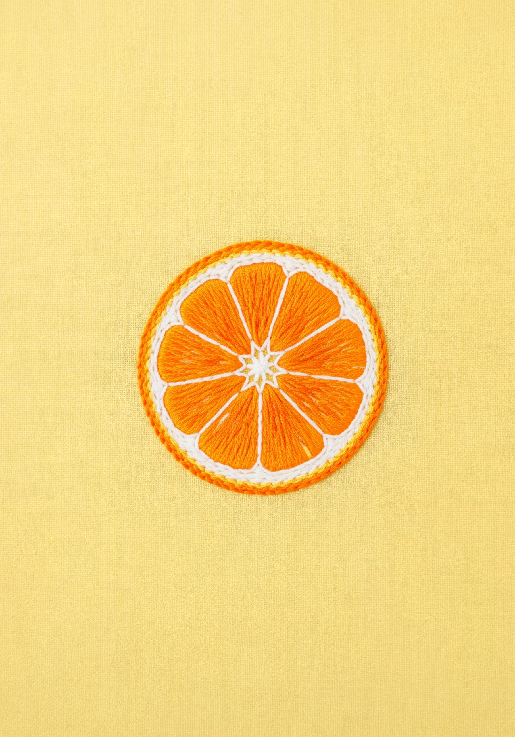 An embroidered orange slice with satin-stitched segments and a thick white outline.