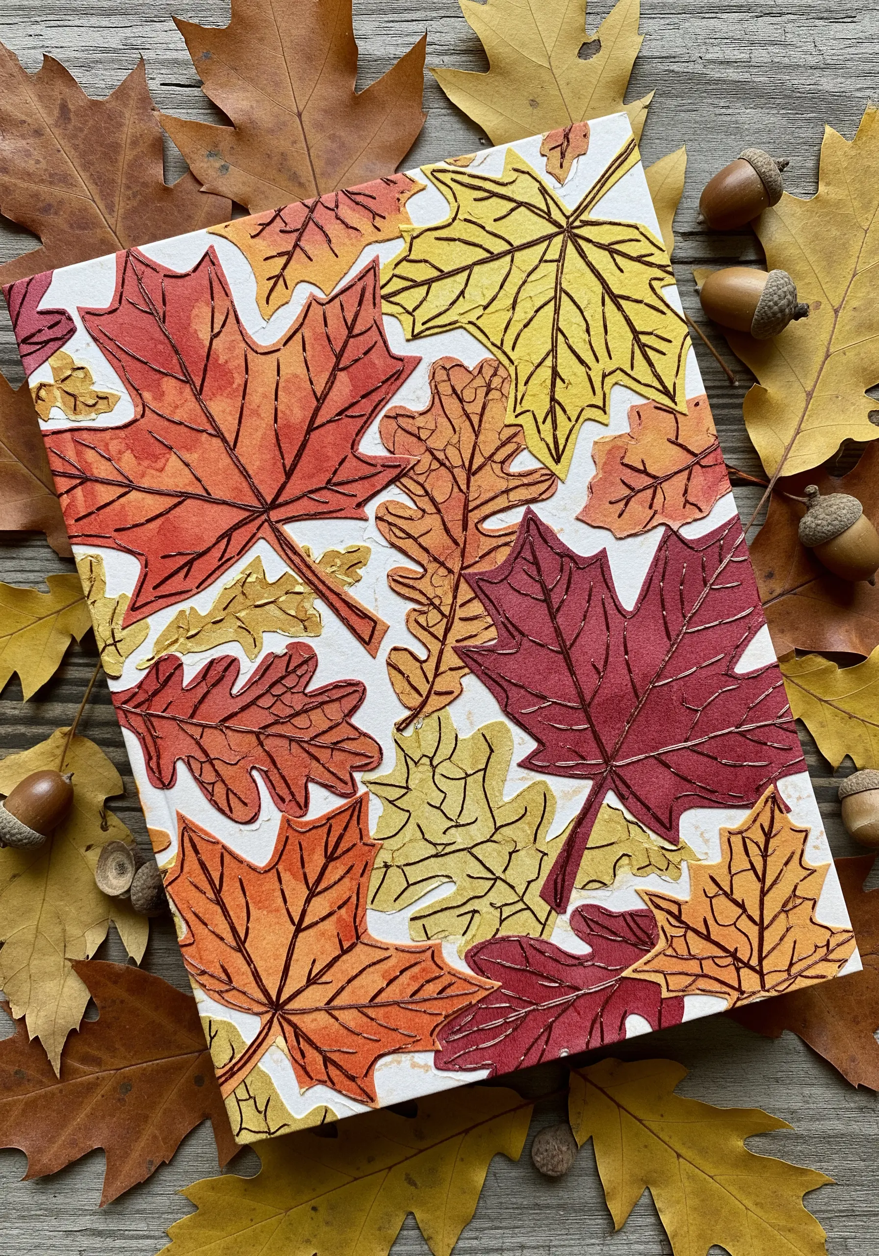 Autumn leaves painted with watercolor on paper, with dark thread stitched for veins and outlines.