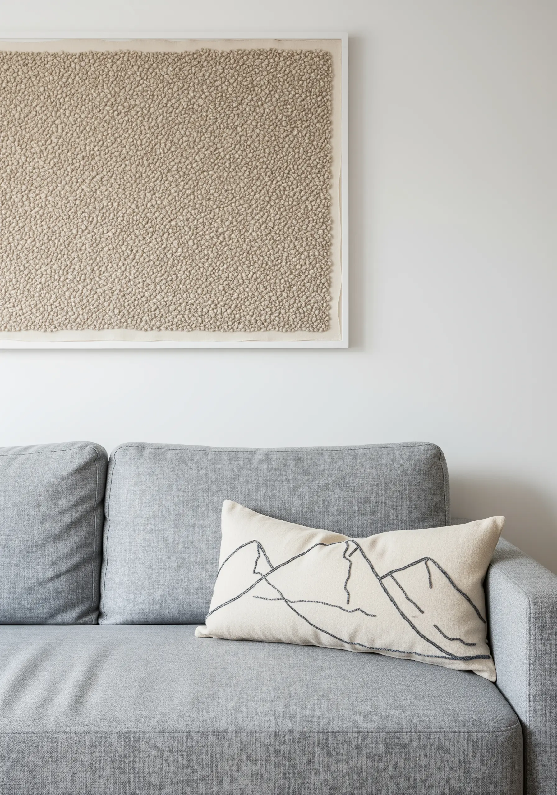 Minimalist mountain range outline stitched in black on an off-white pillow