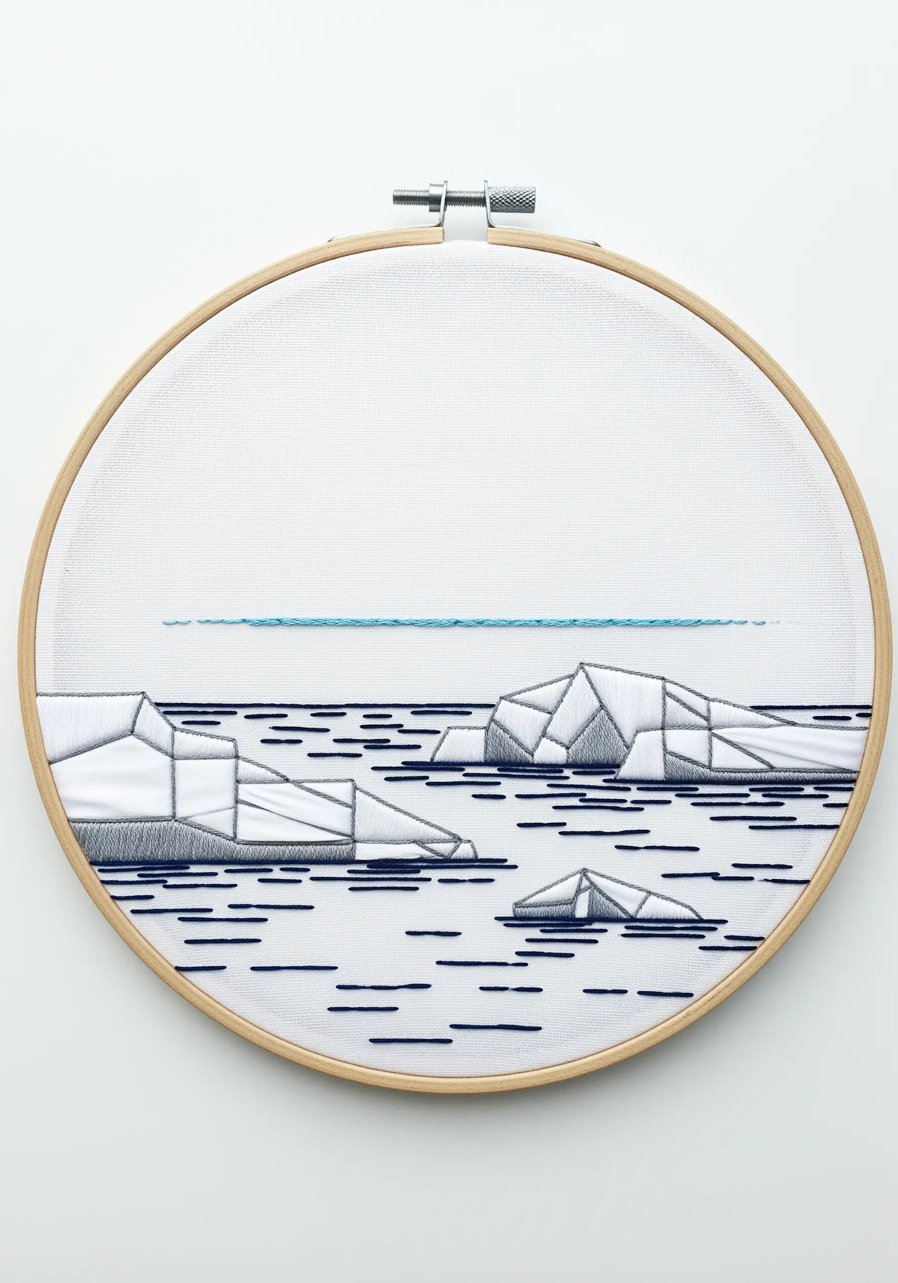 Minimalist geometric embroidery of icebergs using satin stitch and negative space on white fabric.