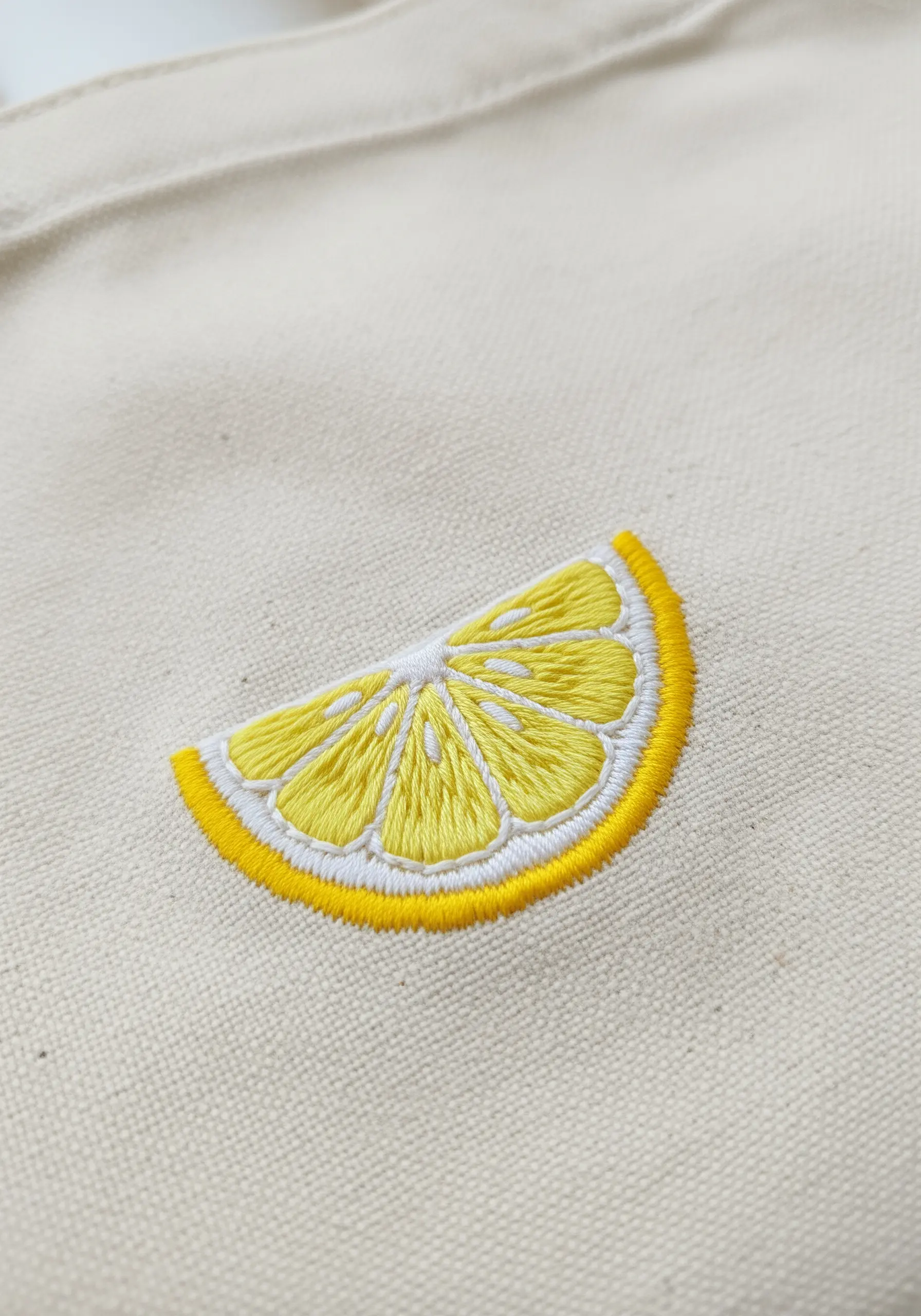 Brightly embroidered lemon slice with detailed segments outlined in white and yellow.