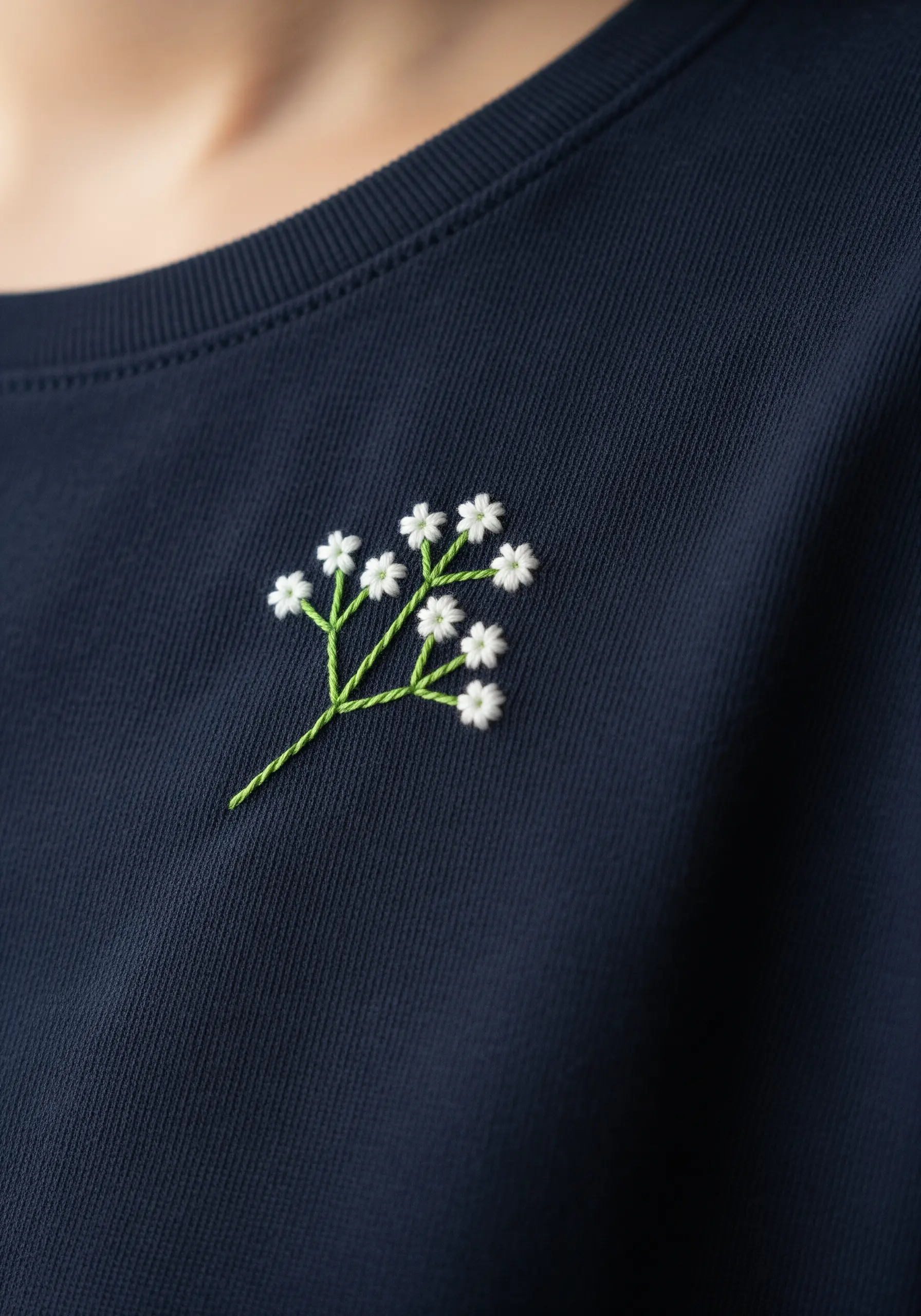 A small sprig of baby's breath with tiny white flowers on a dark navy sweatshirt.
