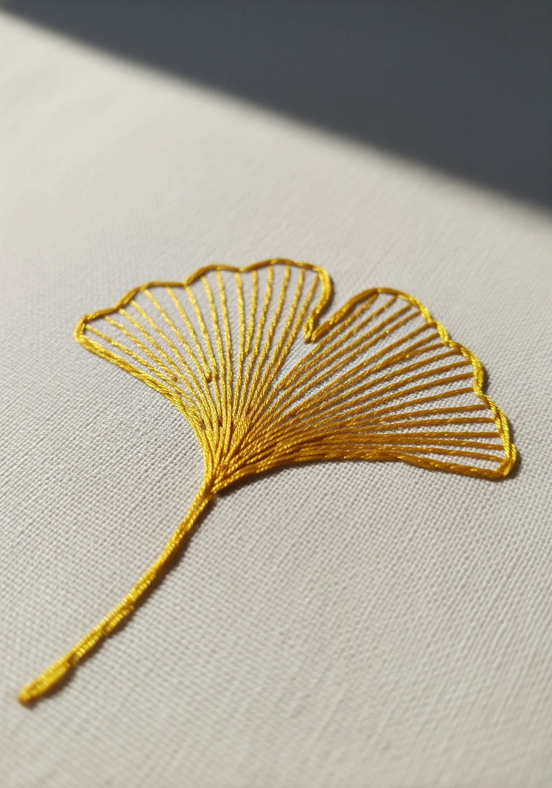 A golden yellow ginkgo leaf embroidered with an open fishbone stitch.