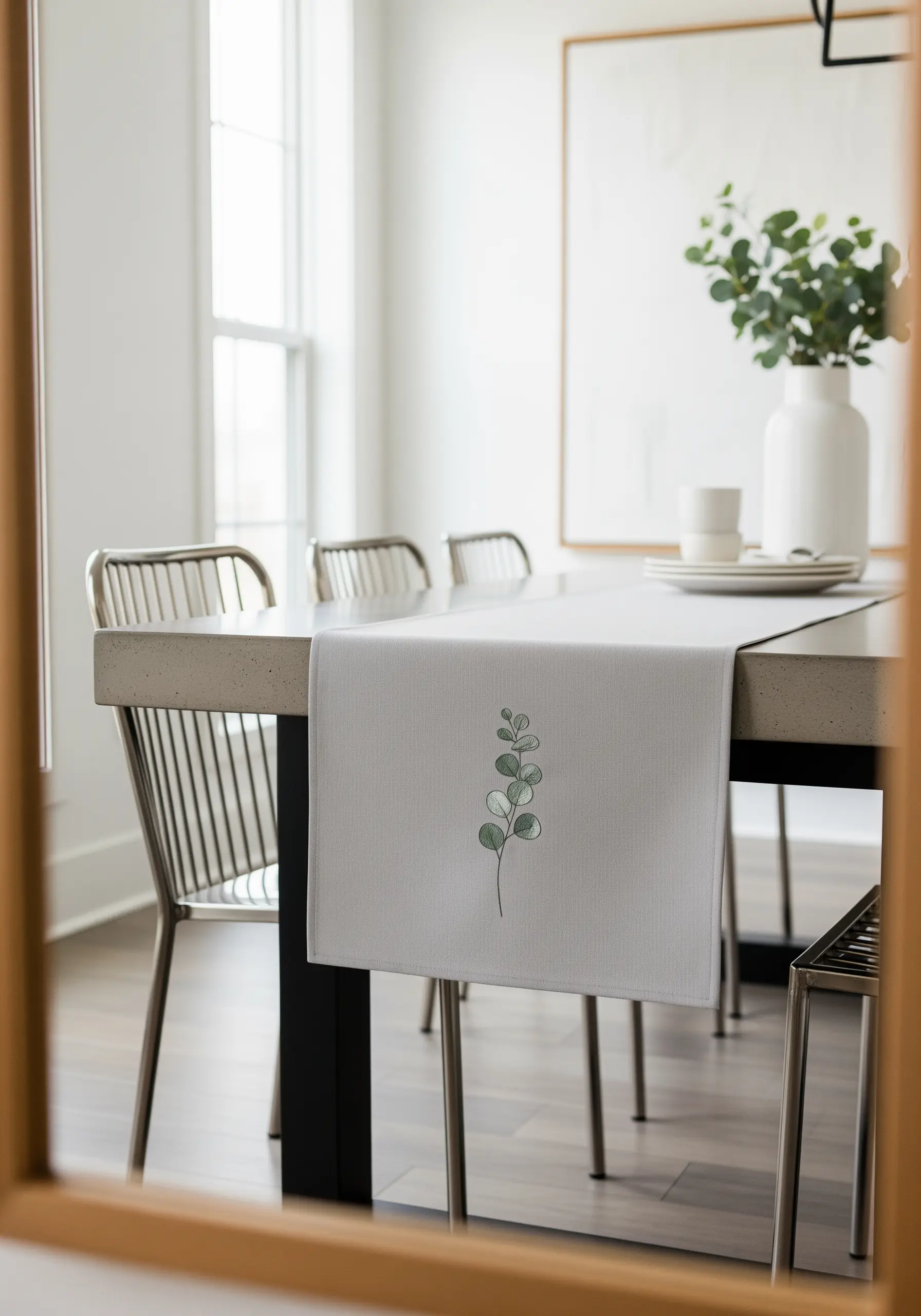 A single eucalyptus branch with softly shaded leaves on a light gray table runner