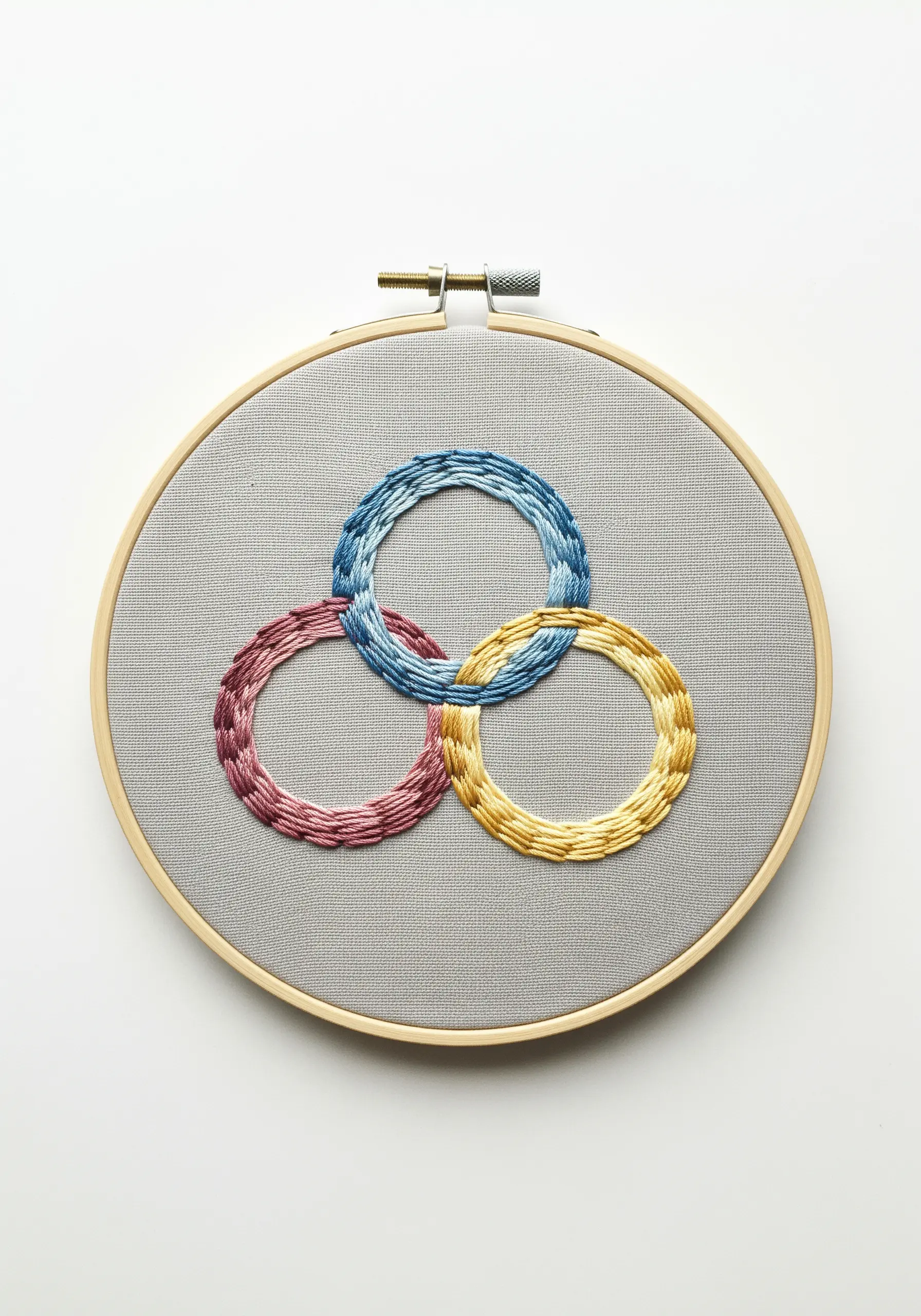 Three interlocking rings embroidered with a textured, multicolored brick stitch.