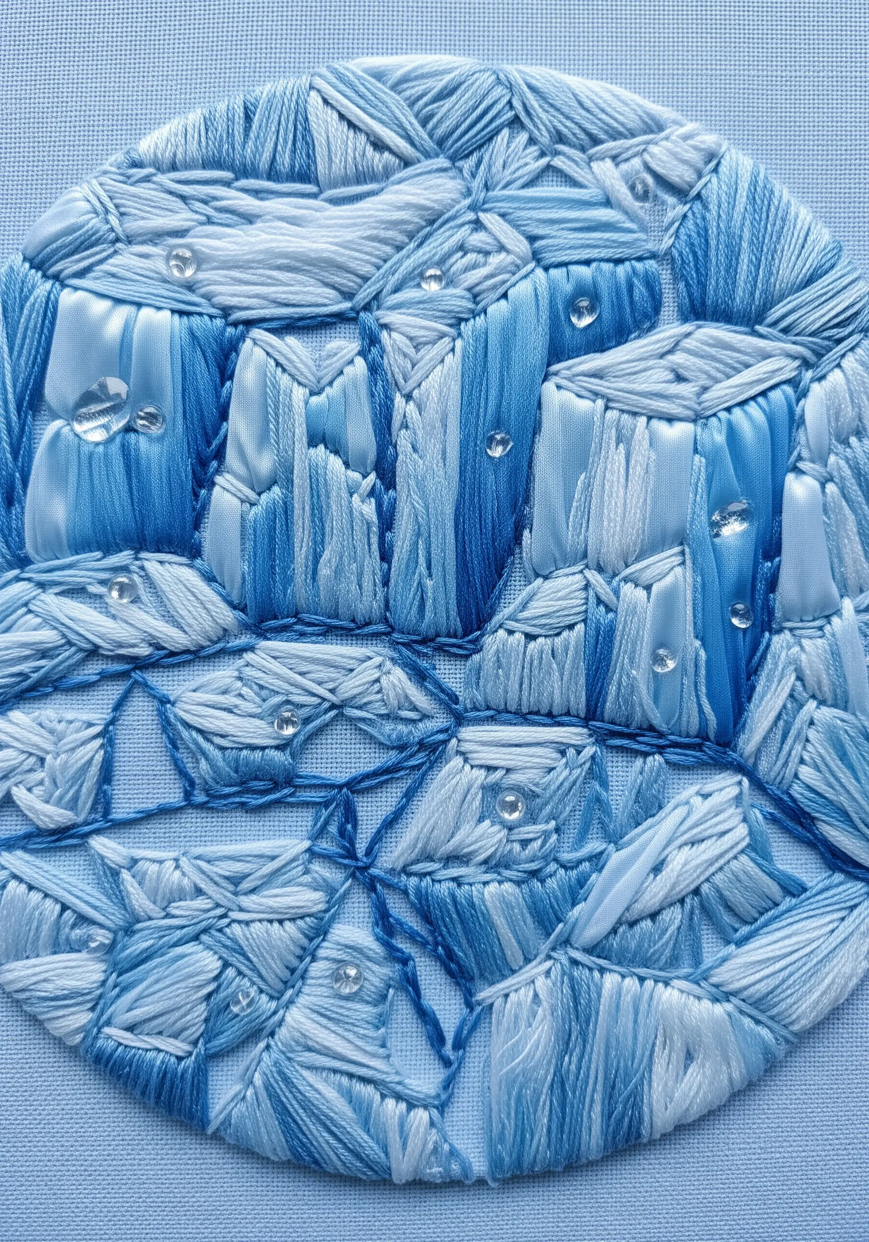 Abstract embroidery of blue and white icebergs using silk ribbon and thread, with bead accents.