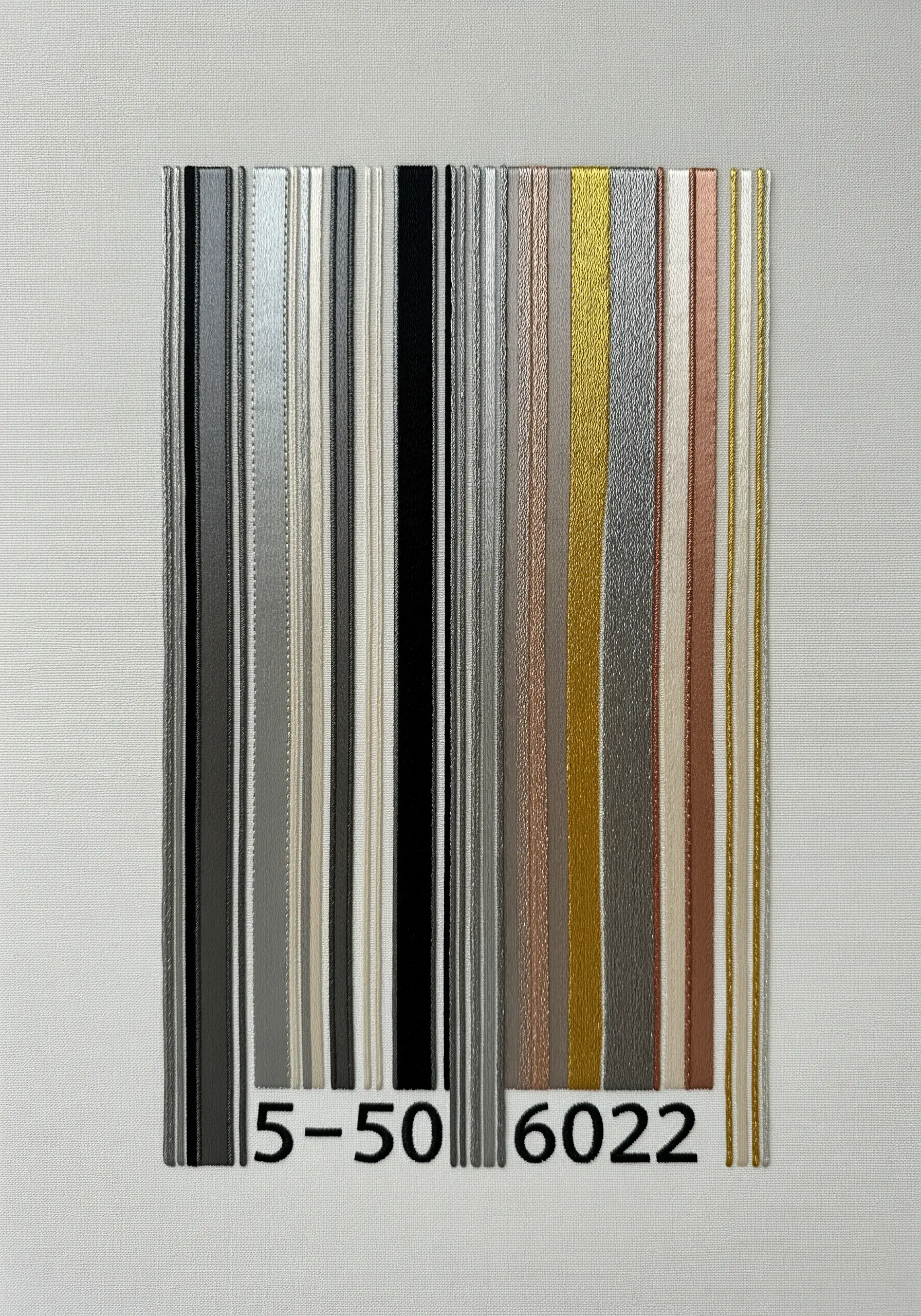 A barcode design created with vertical strips of metallic ribbons and threads in various finishes.