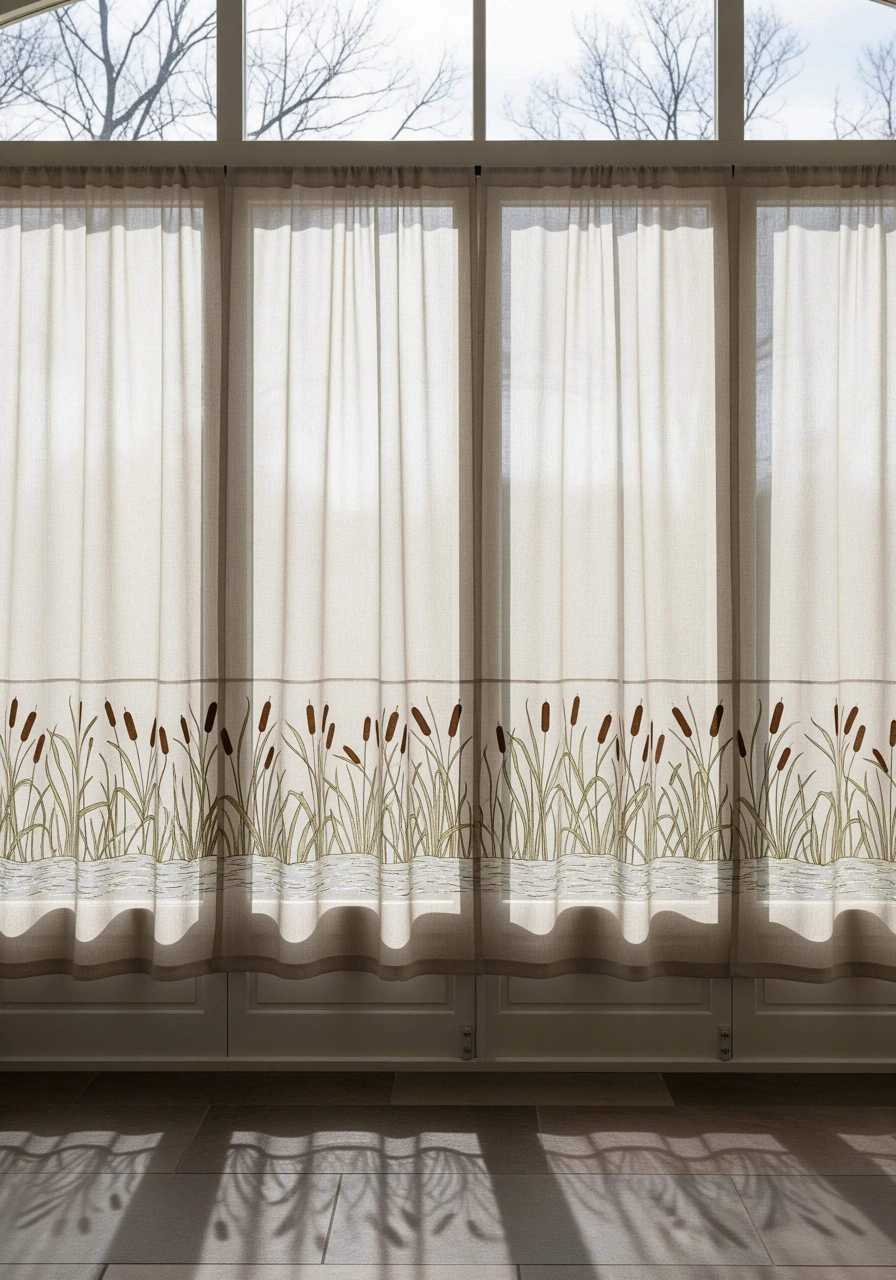 Sheer linen curtains with an embroidered border of cattails and reeds along the bottom edge.