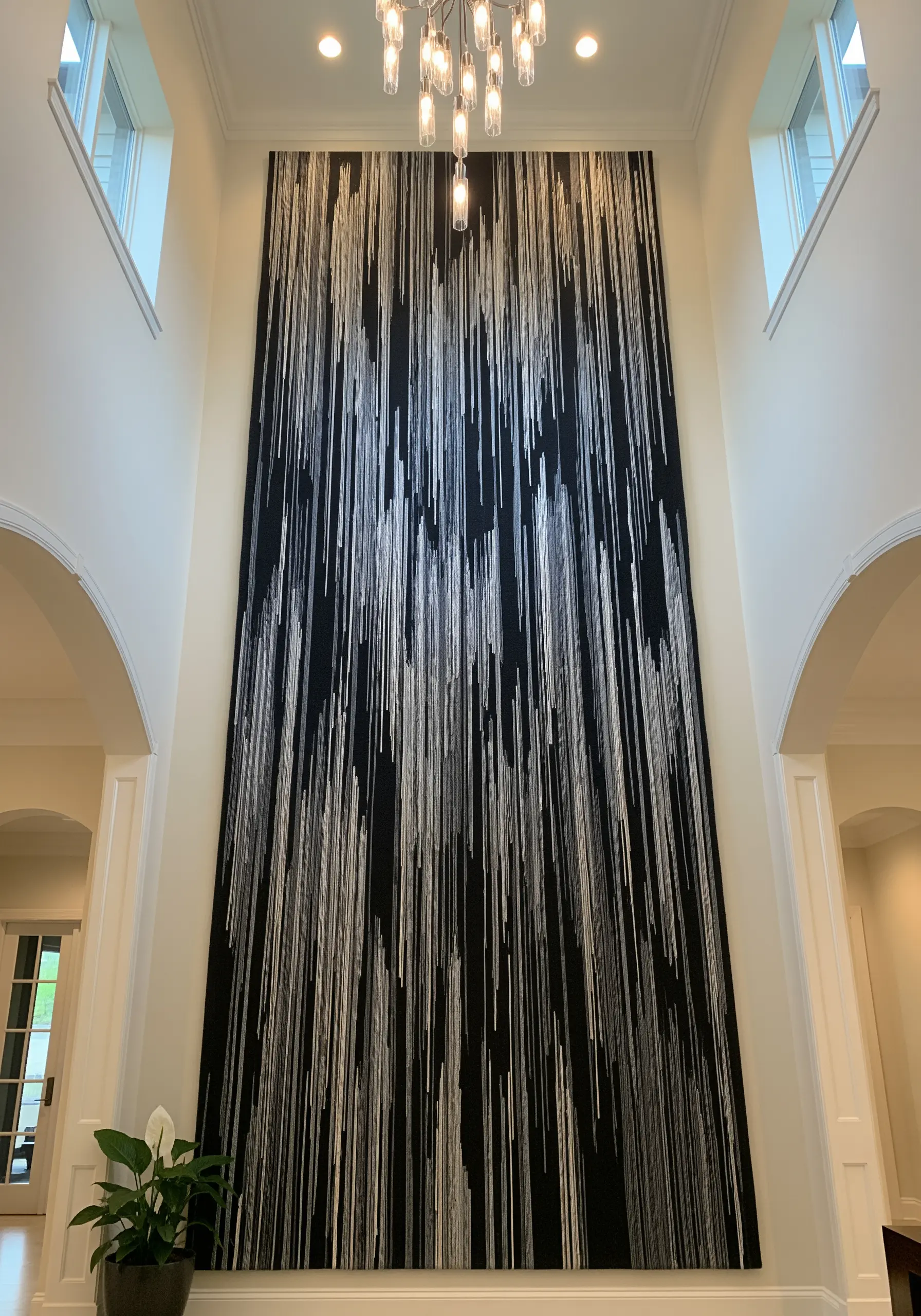 A massive, floor-to-ceiling black tapestry with vertical lines of white and silver thread.