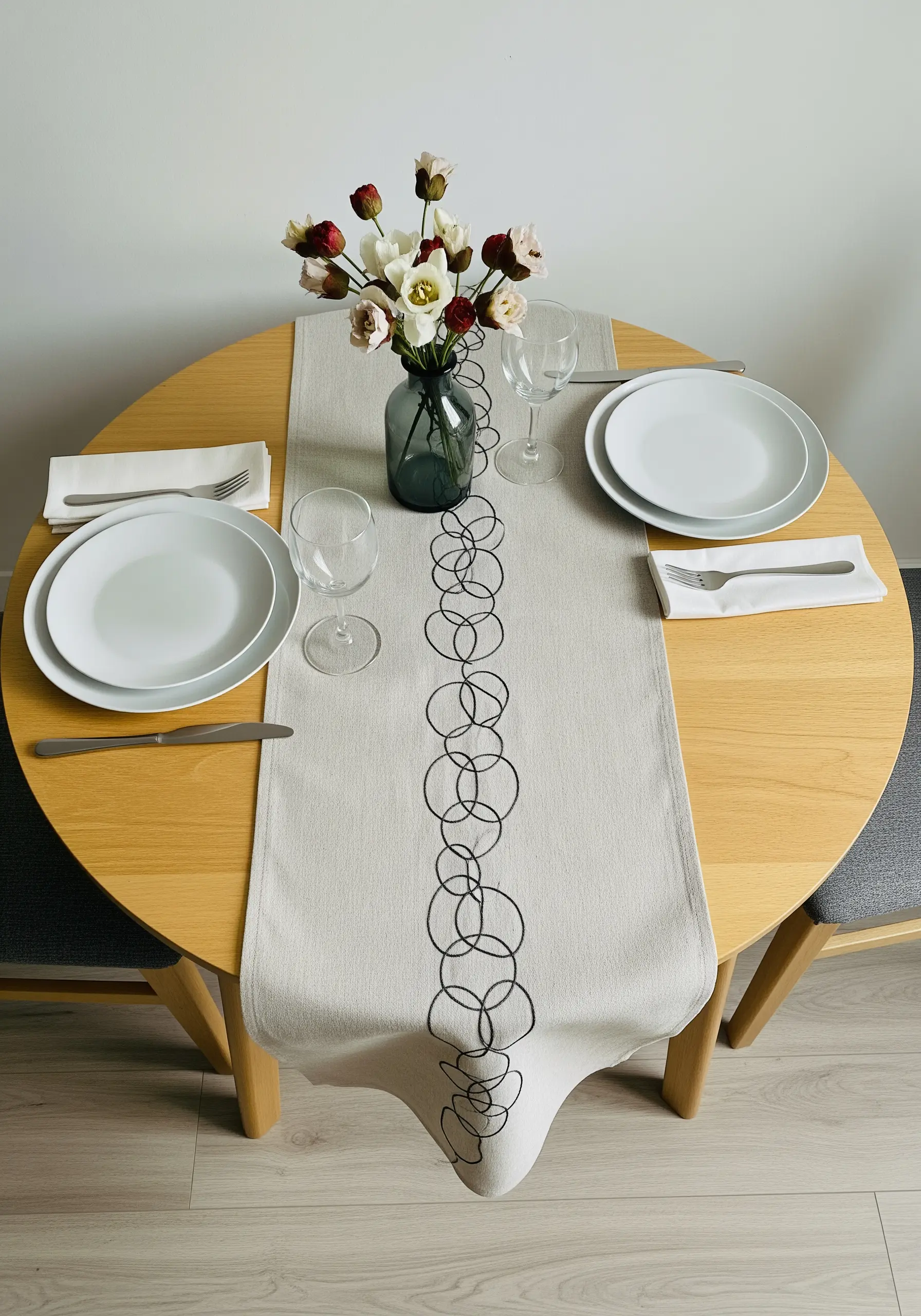 A minimalist table runner embroidered with a continuous chain of interlocking black circles.
