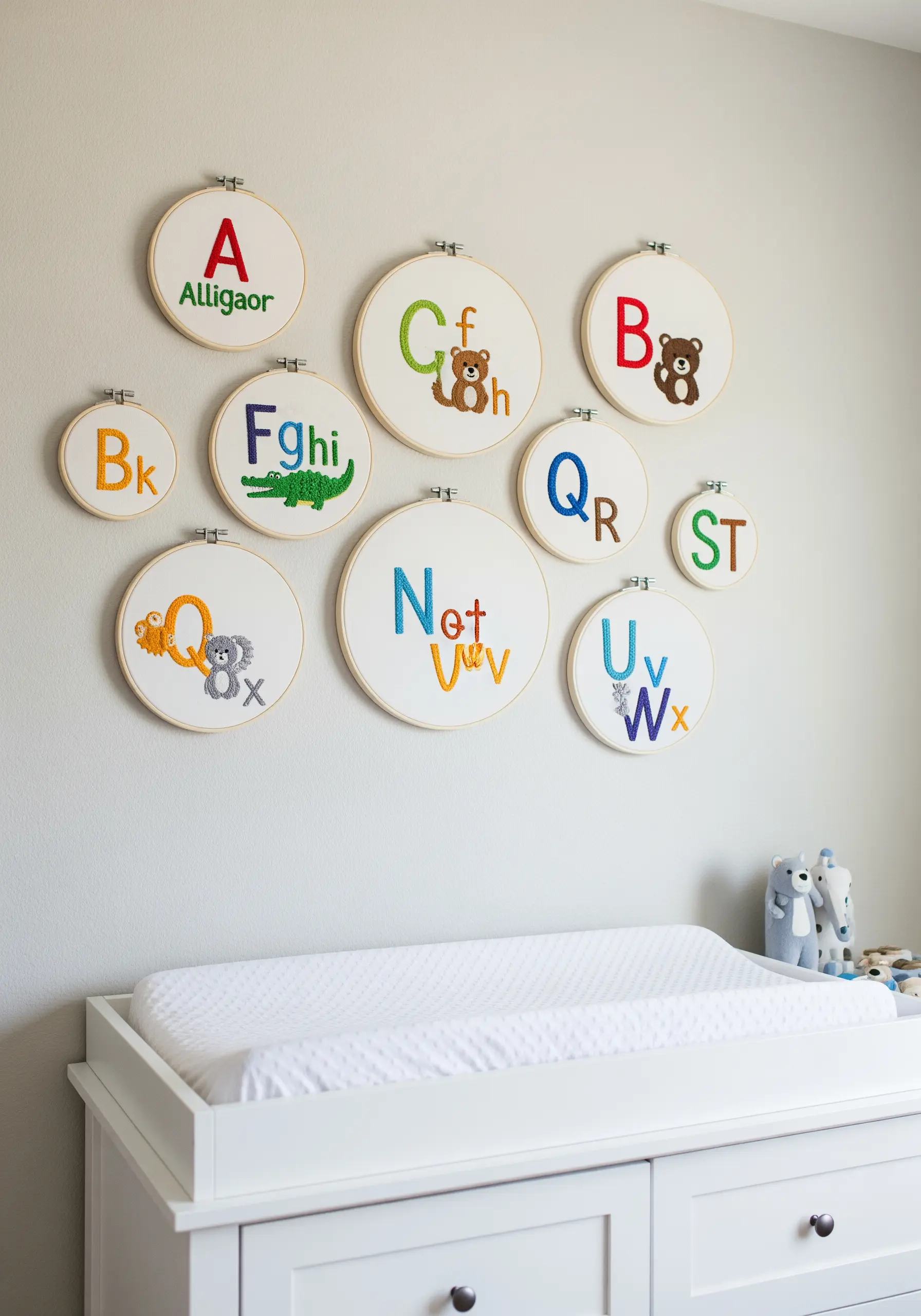 A nursery wall decorated with embroidered hoops for different letters of the alphabet with animals.