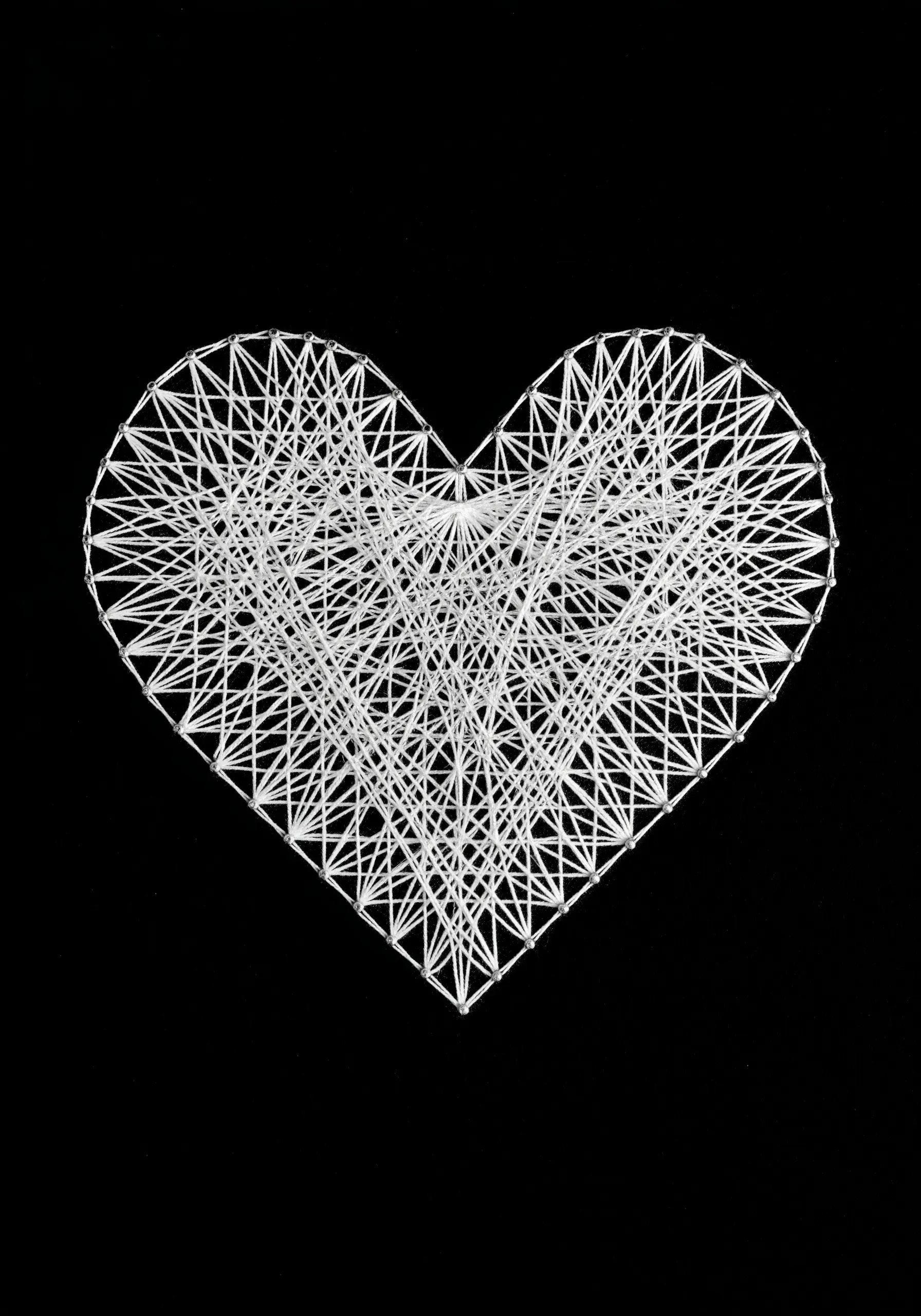 A highly intricate web of white string art creating a heart shape on a solid black background.