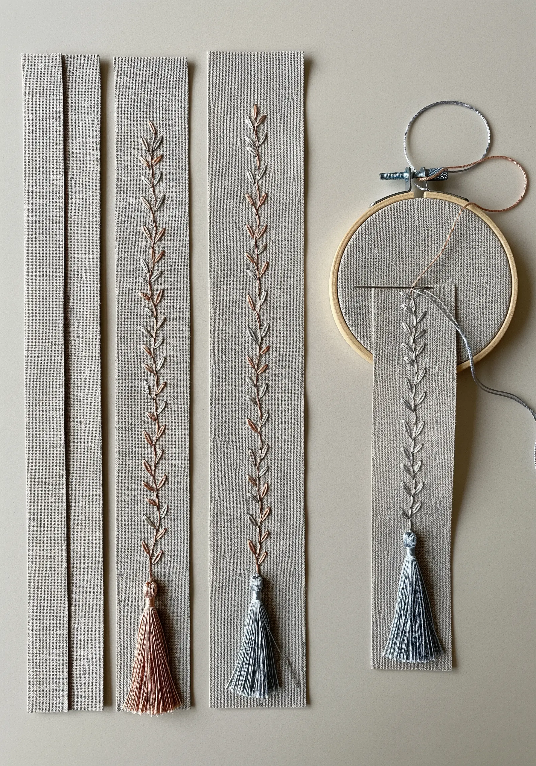 Hand-embroidered bookmarks with delicate leaf vines and matching tassels being stitched.