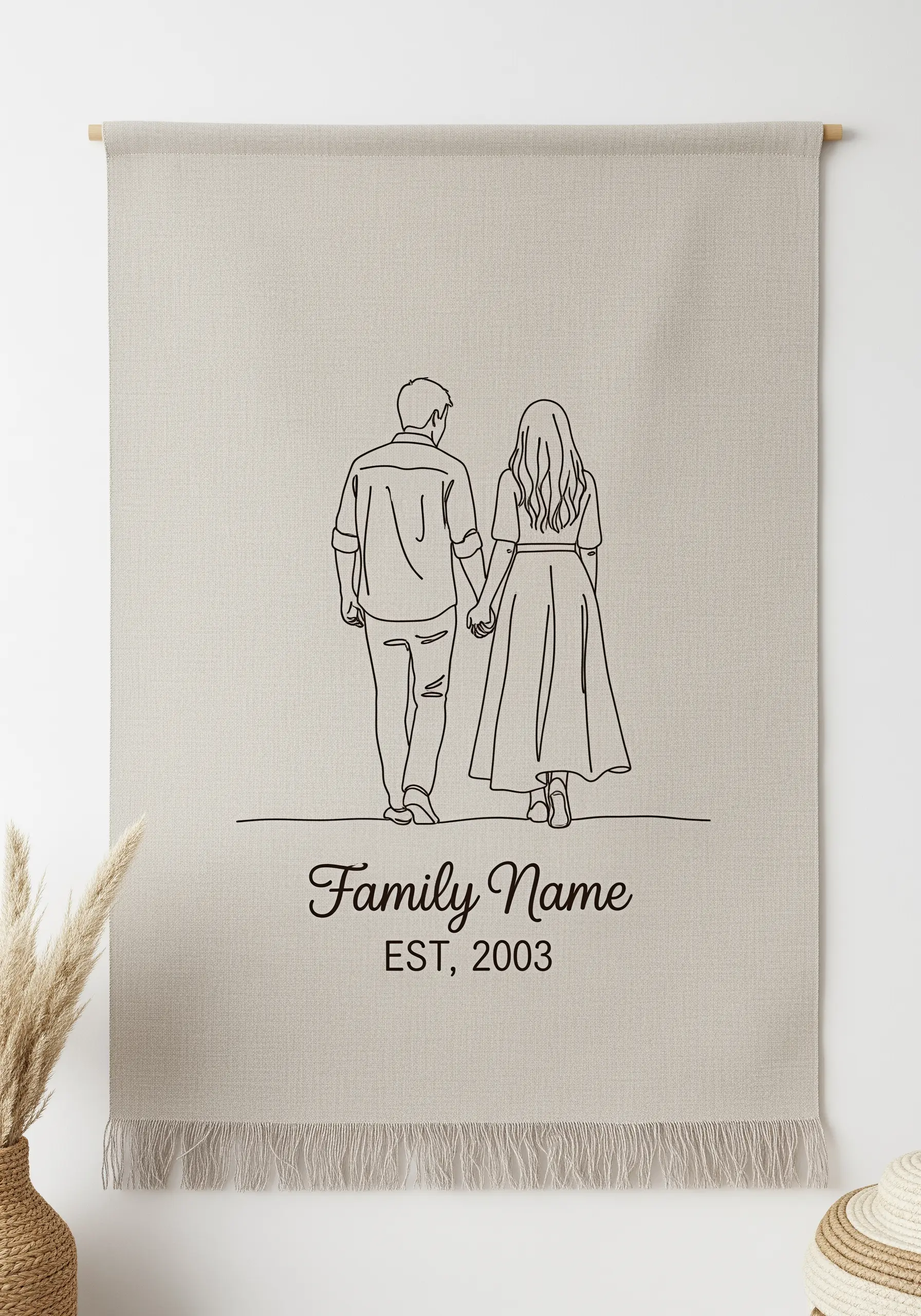 A couple holding hands embroidered on a linen wall hanging with a personalized family name and date.