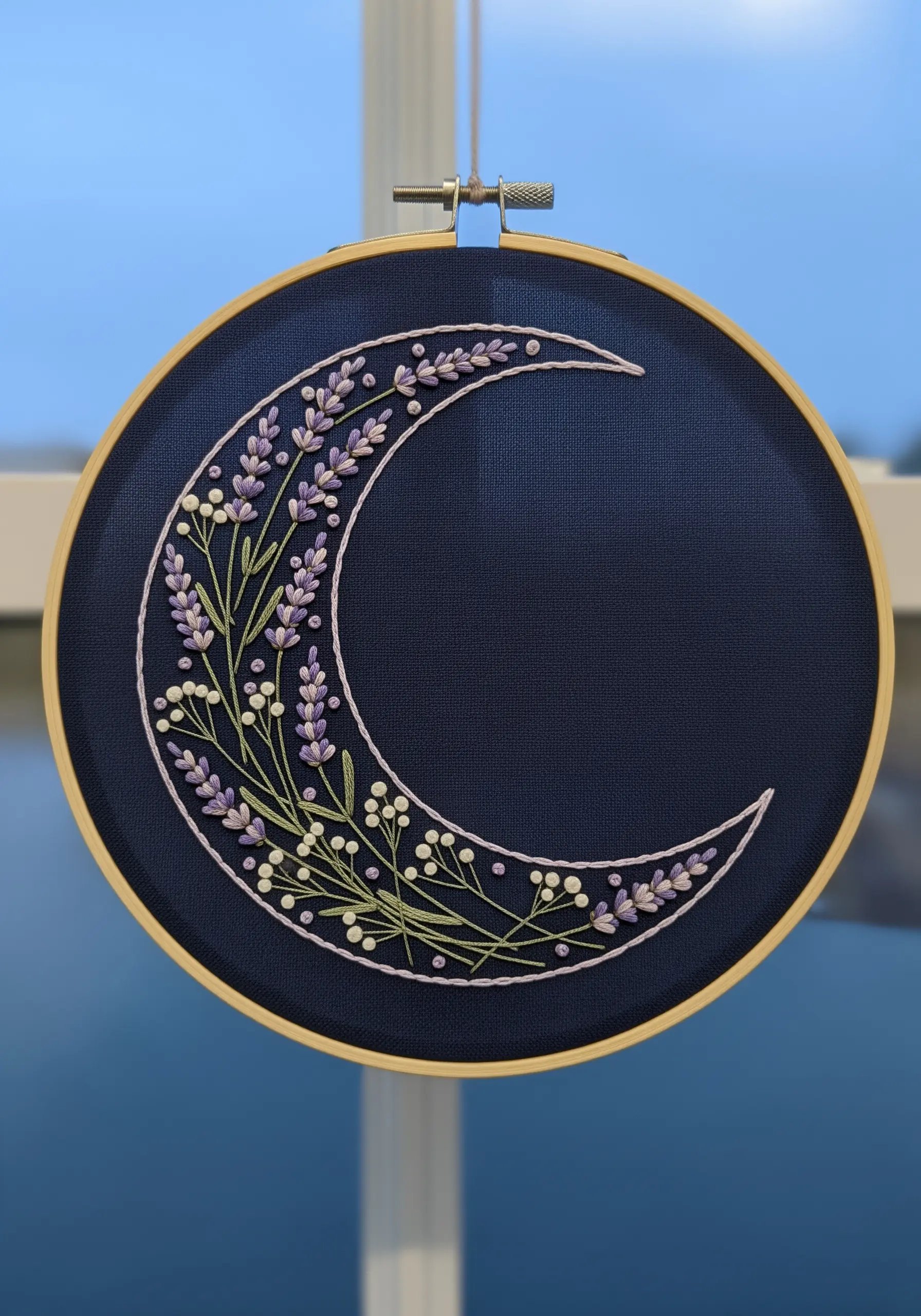A crescent moon filled with an arrangement of lavender and small white flowers on navy fabric.