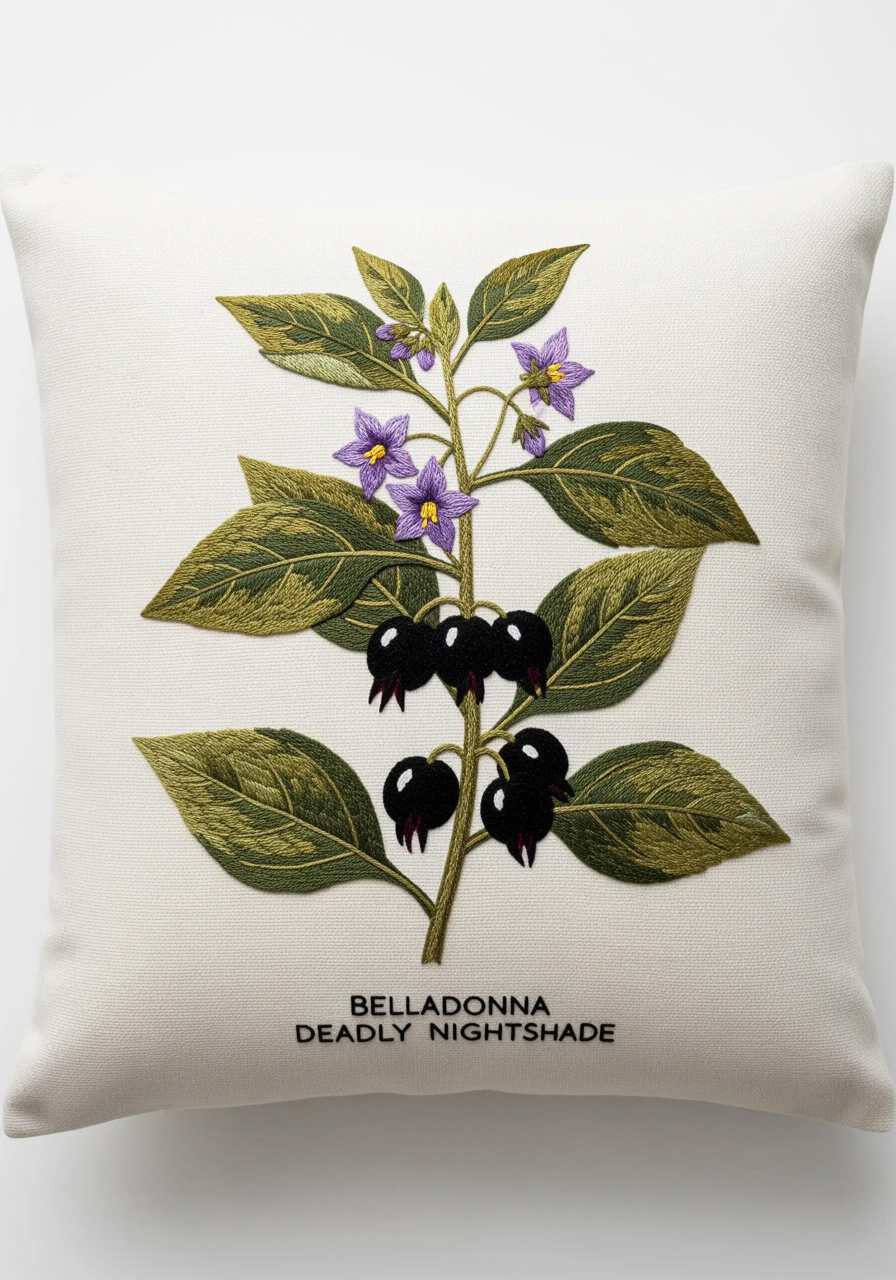 A scientific botanical illustration of a Belladonna plant embroidered on a white cushion.