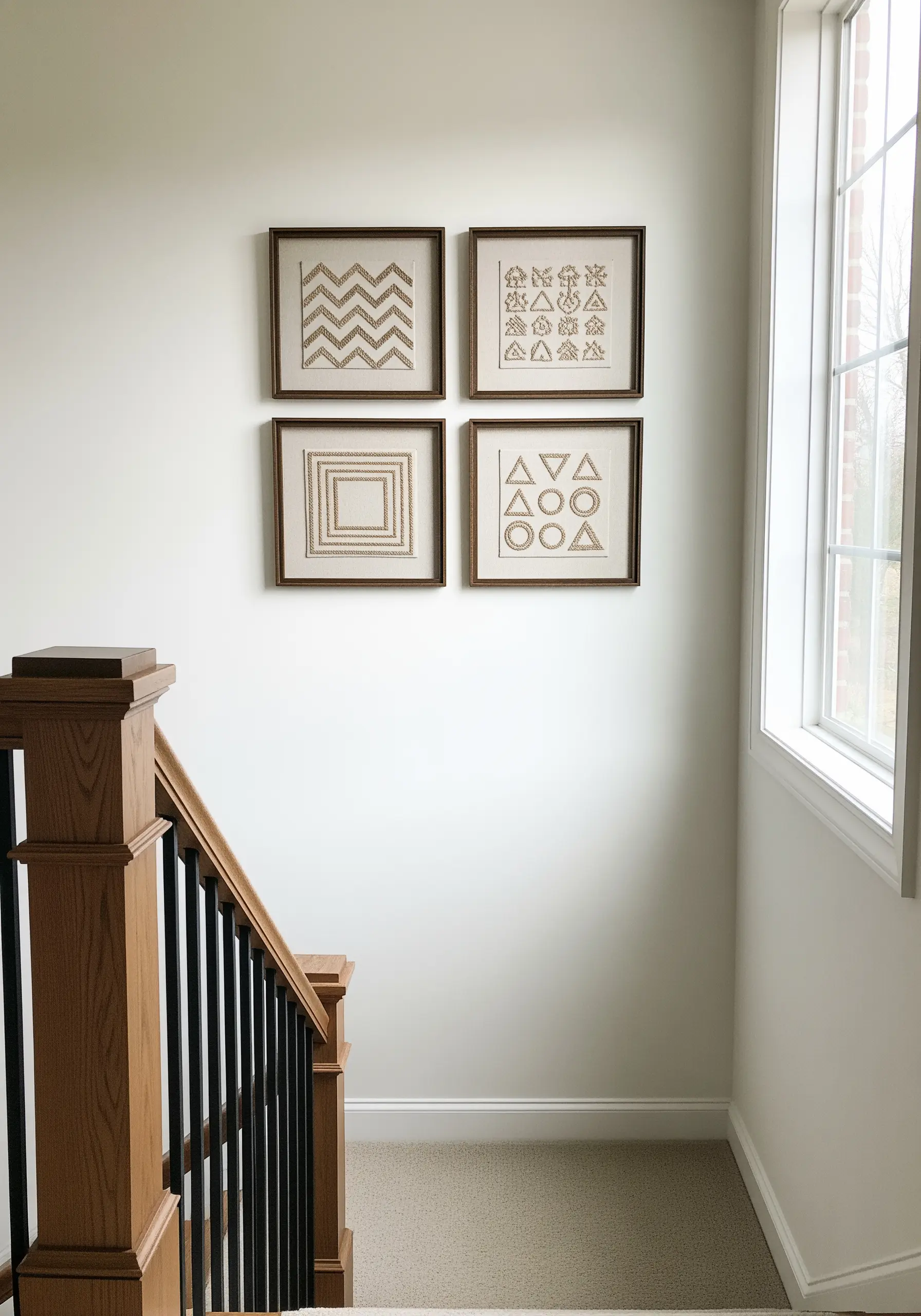 Four framed embroidery pieces with geometric patterns in gold thread, hung in a square formation.