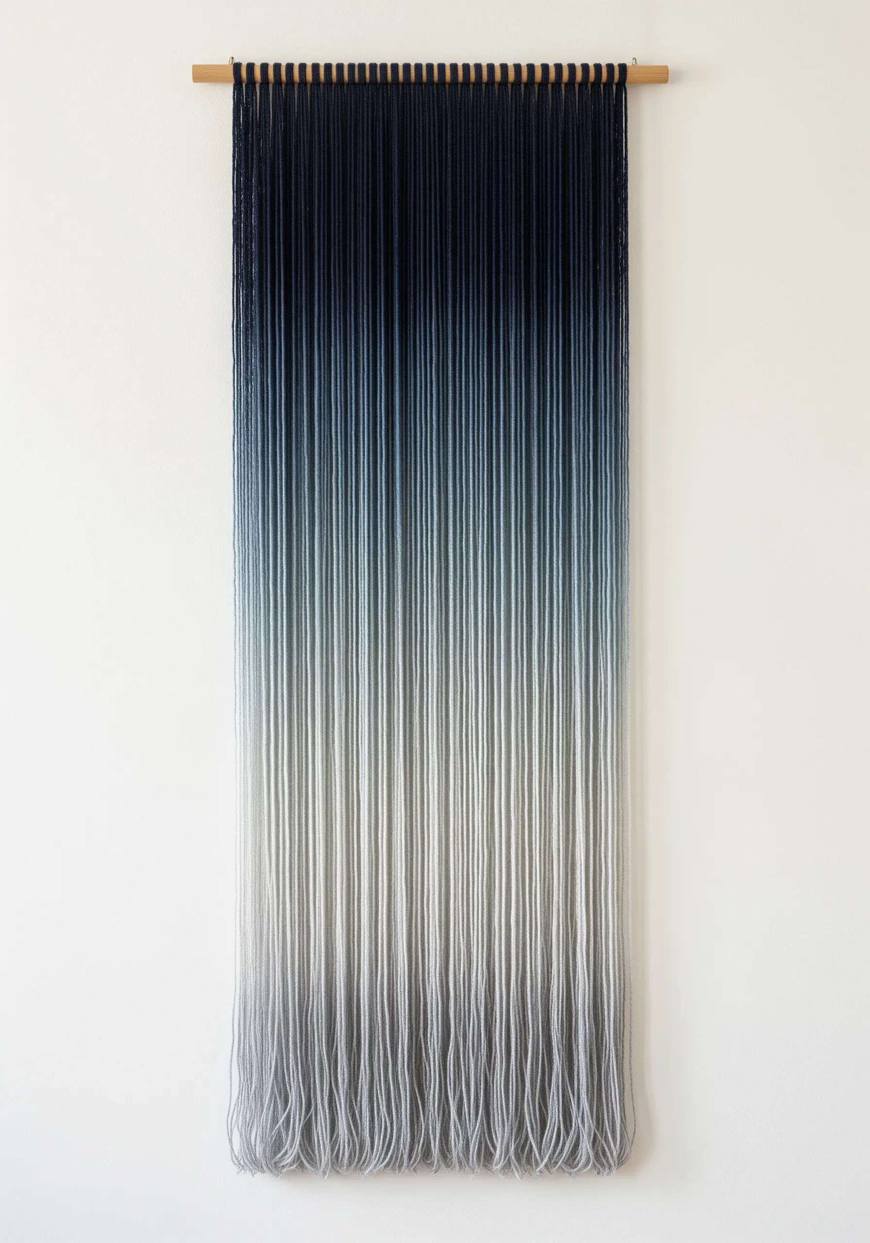 A minimalist yarn wall hanging featuring a smooth gradient from dark blue to light gray.