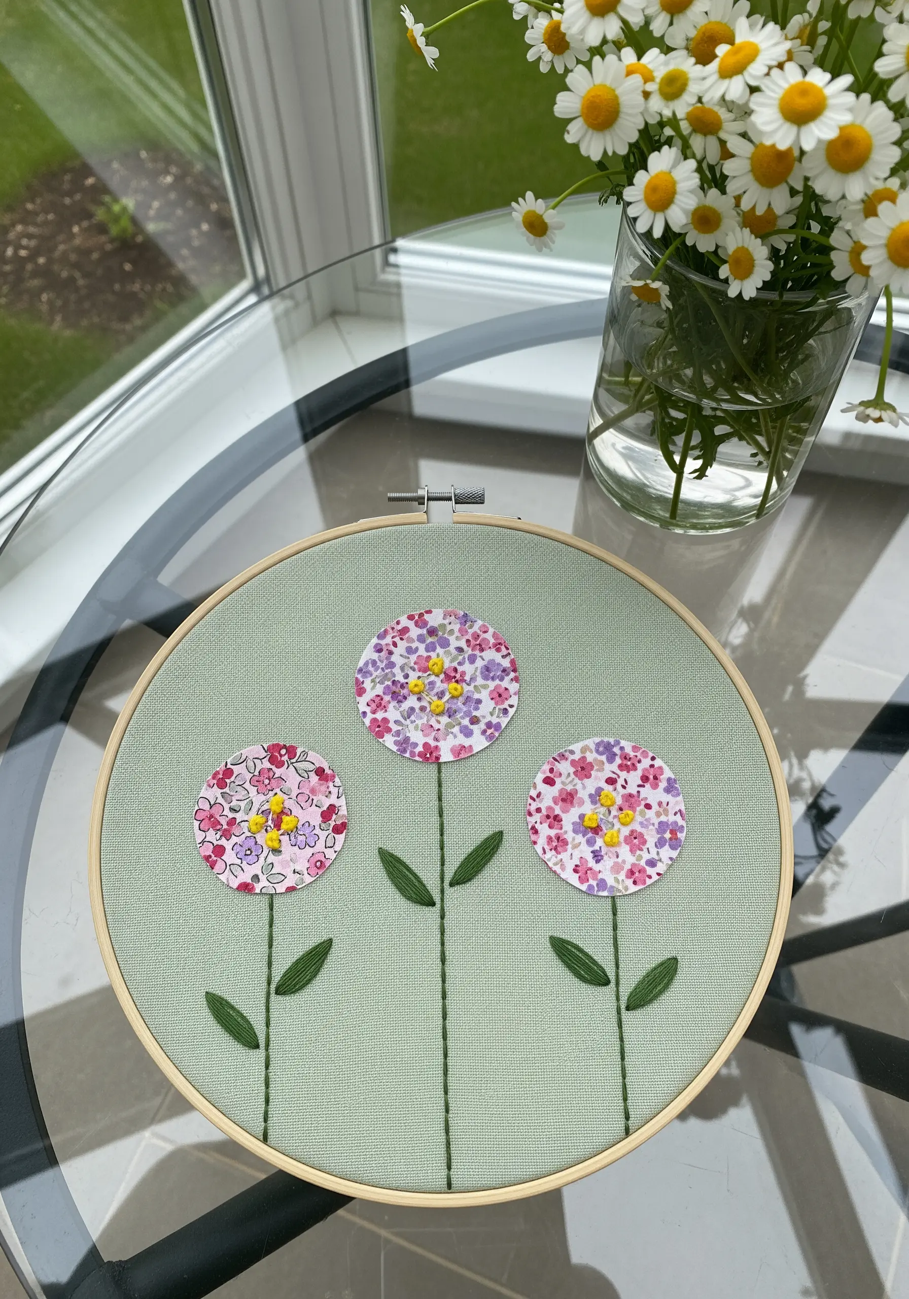 Three floral fabric circles with yellow French knot centers and embroidered stems.