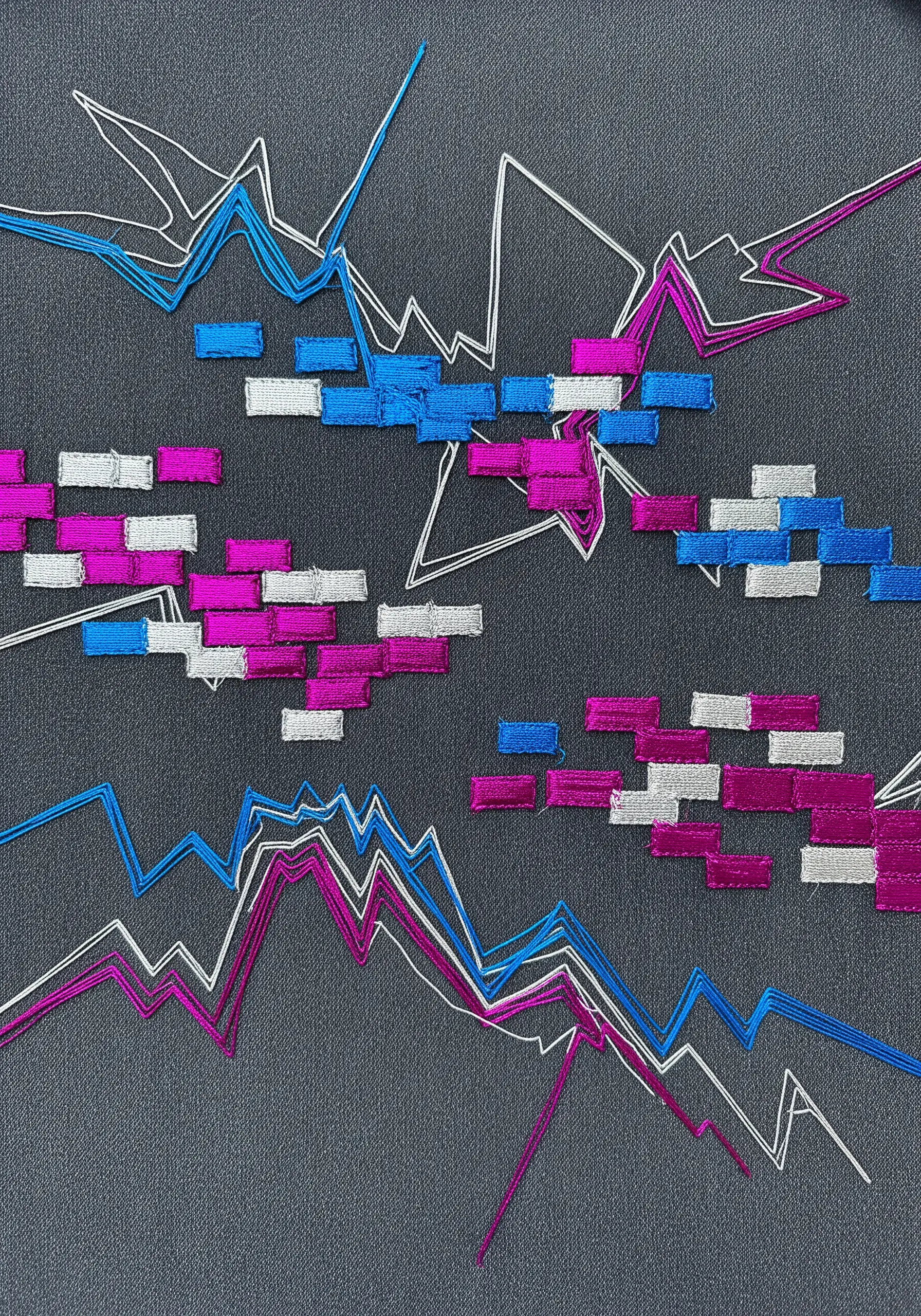 Abstract metallic embroidery with jagged lines and raised satin stitch blocks.