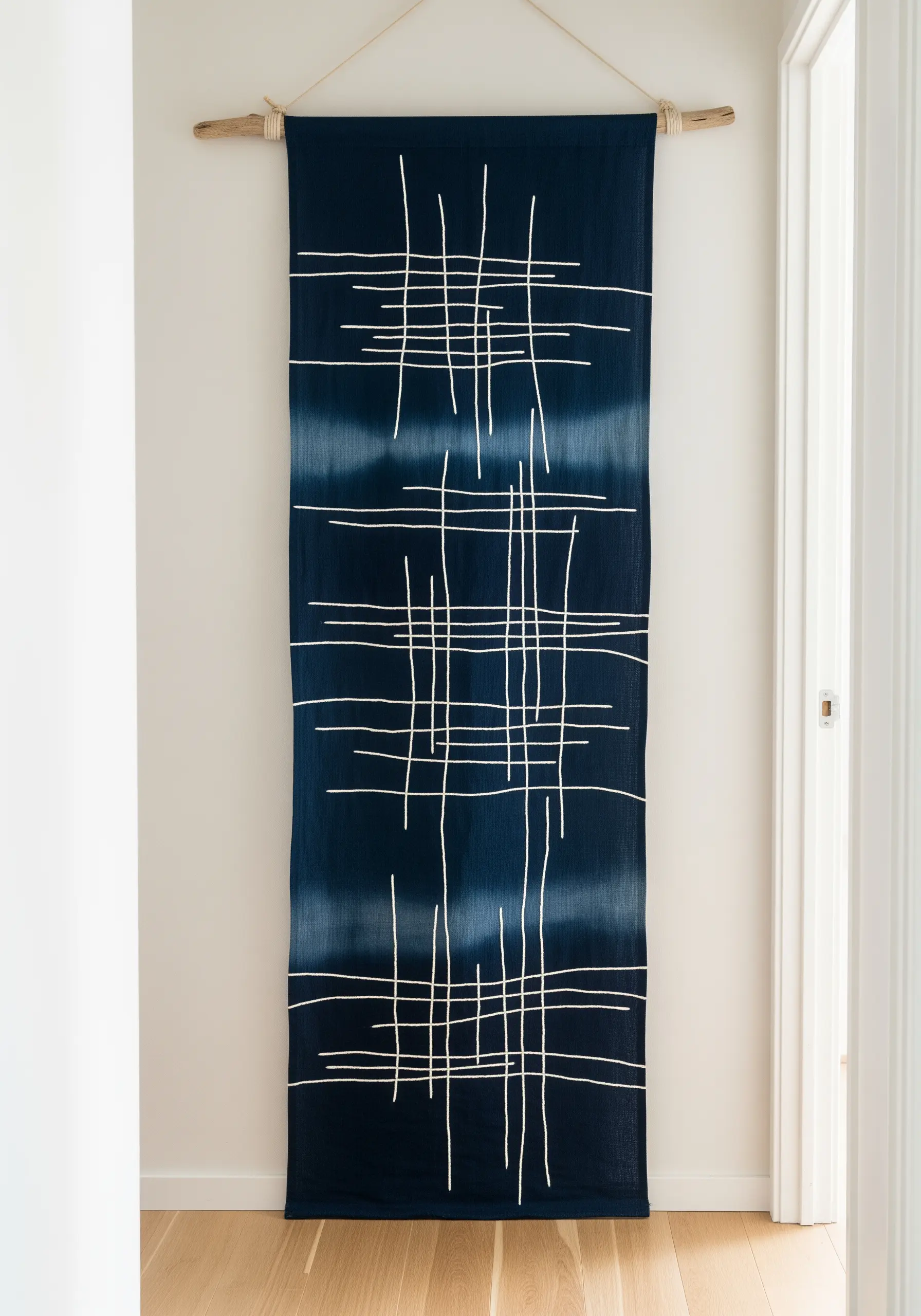 Abstract white lines stitched over a dark blue tie-dyed wall hanging.