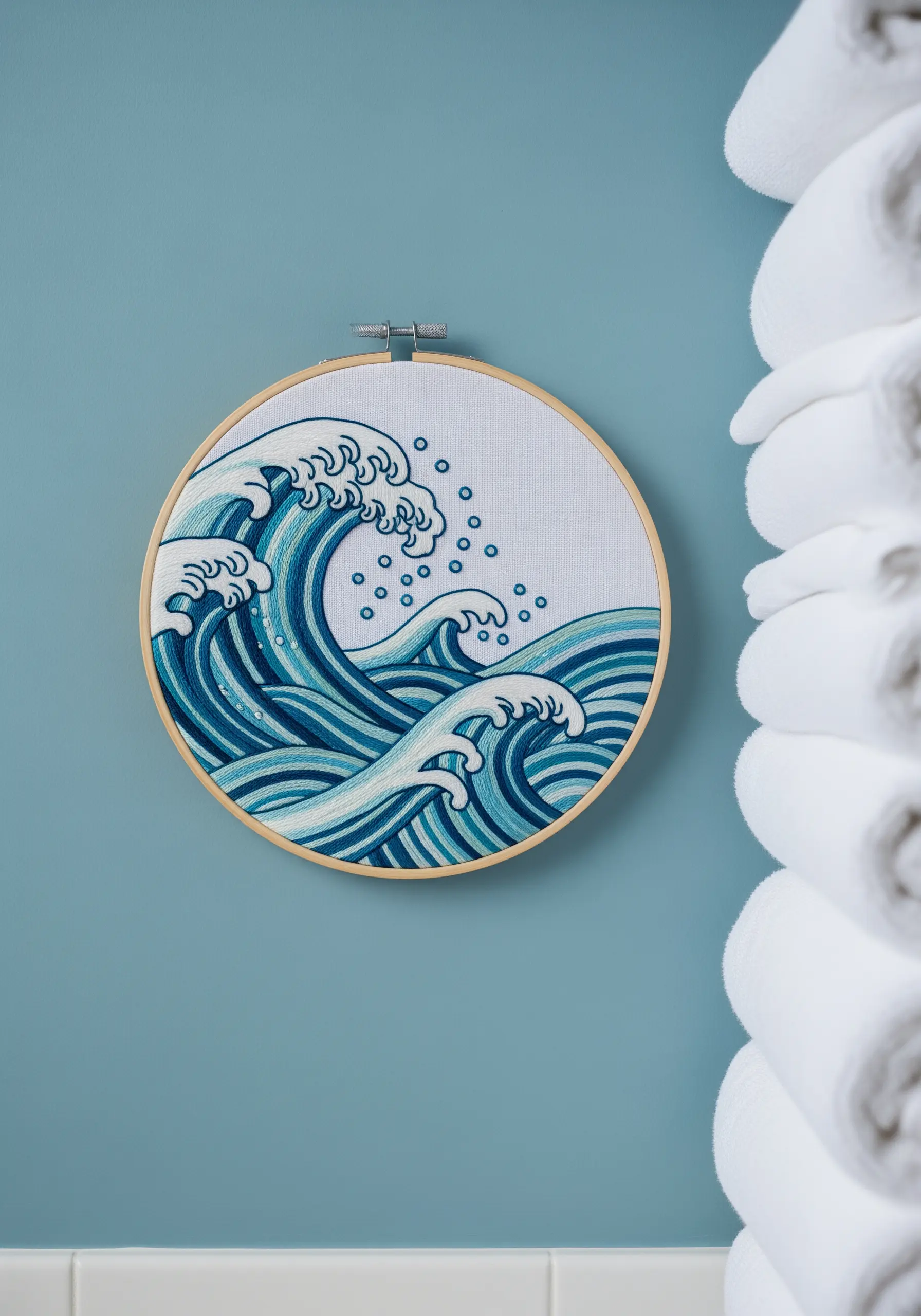 An embroidery hoop with a stylized ocean wave design in various shades of blue.