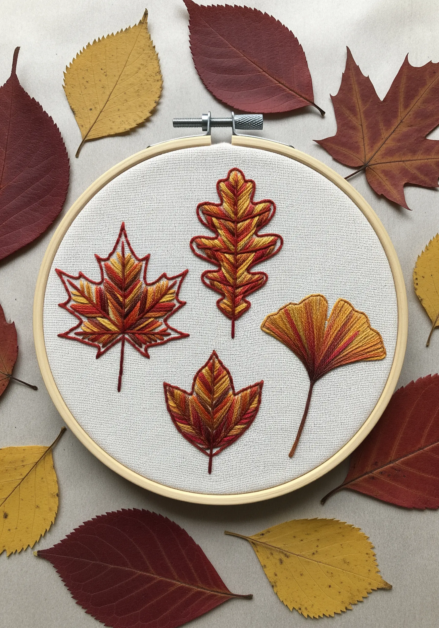 Embroidered autumn leaves in red, orange, and yellow using variegated thread.