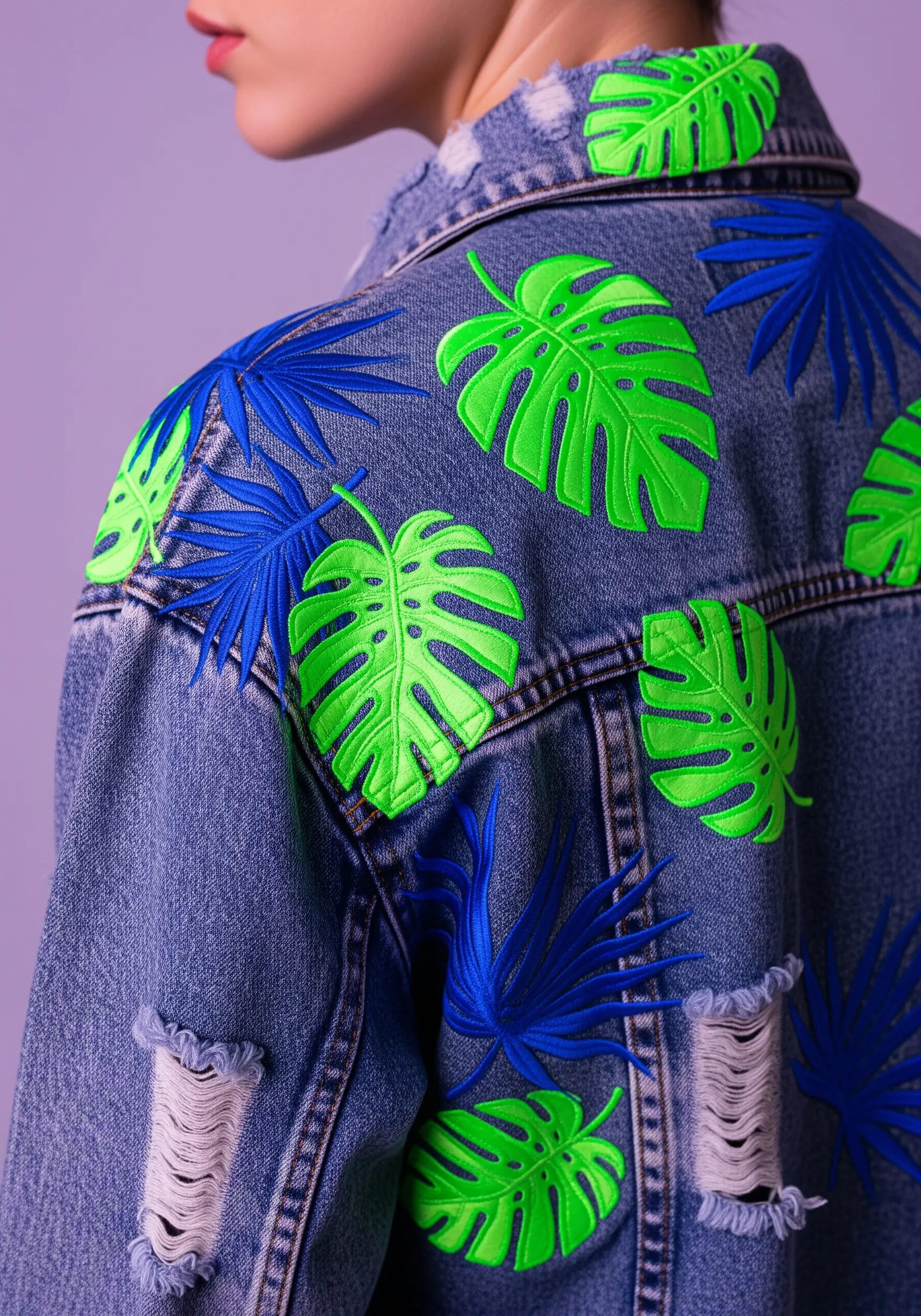 Neon green and royal blue tropical leaves scattered across the back of a distressed denim jacket.