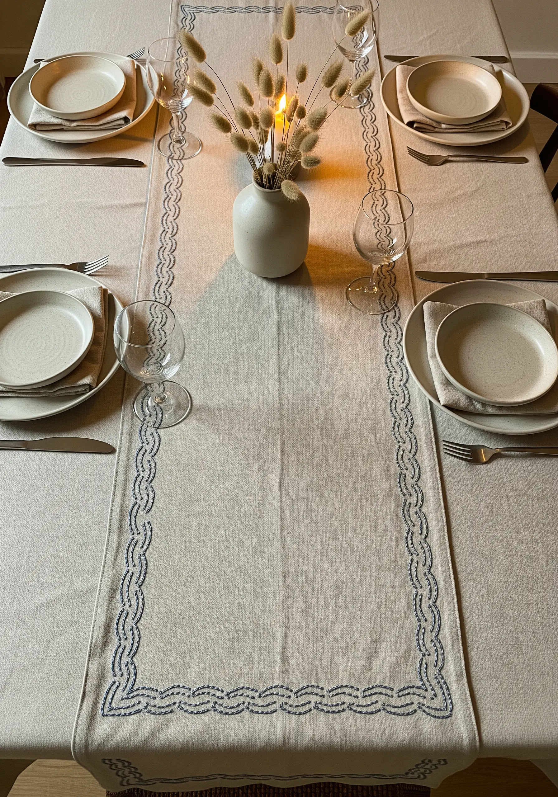 Linen table runner with a delicate, interlocking blue stitch border design.