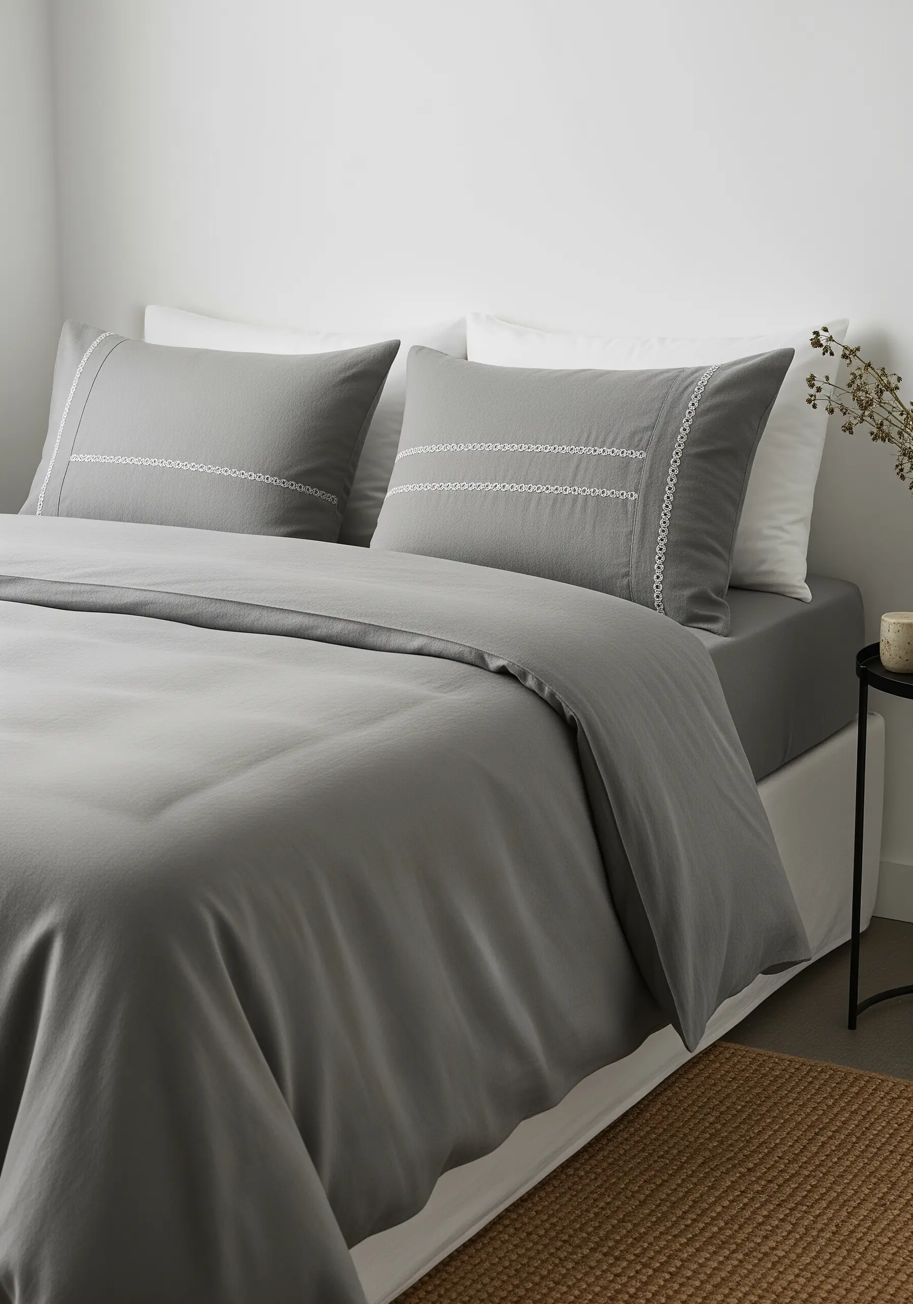 Delicate white lacework-style embroidery bordering grey pillowcases