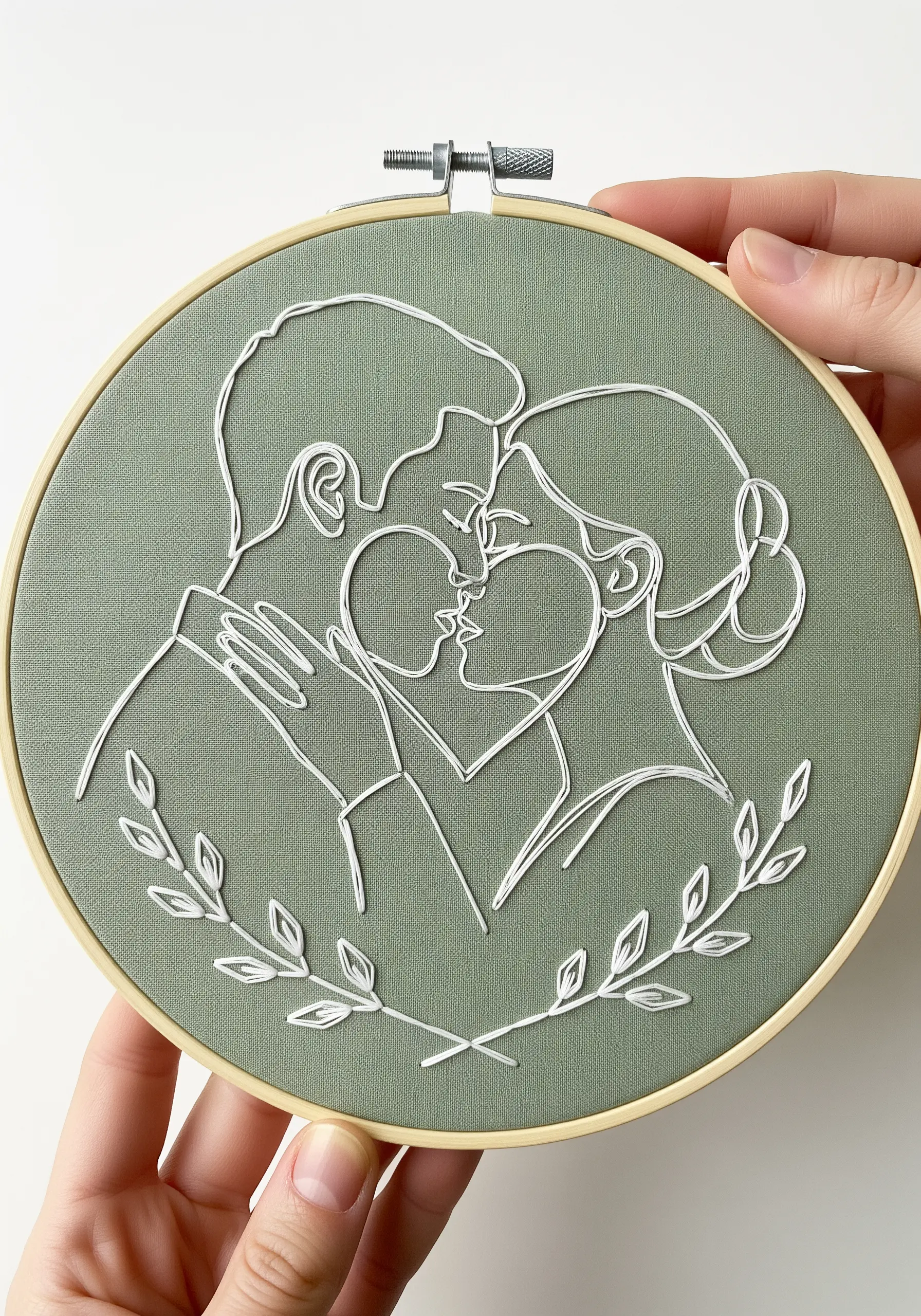 Elegant white line art of a couple kissing on a sage green fabric background.