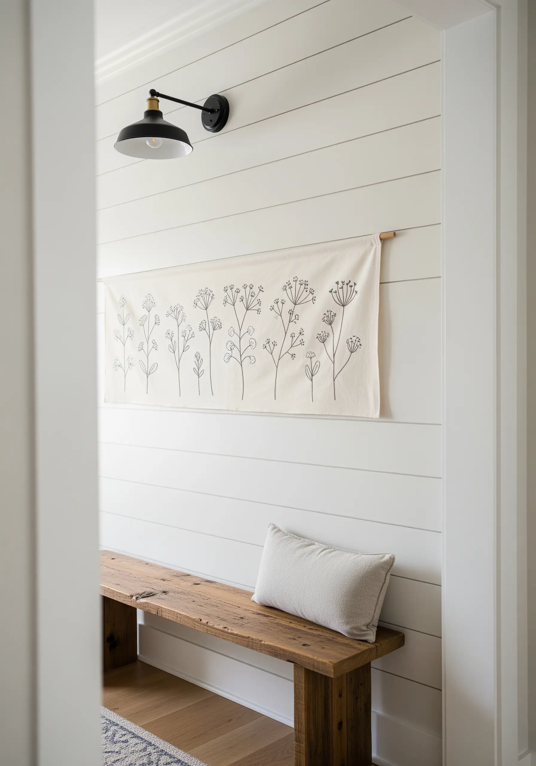 Minimalist black thread embroidery of wildflowers on a long, natural canvas banner.