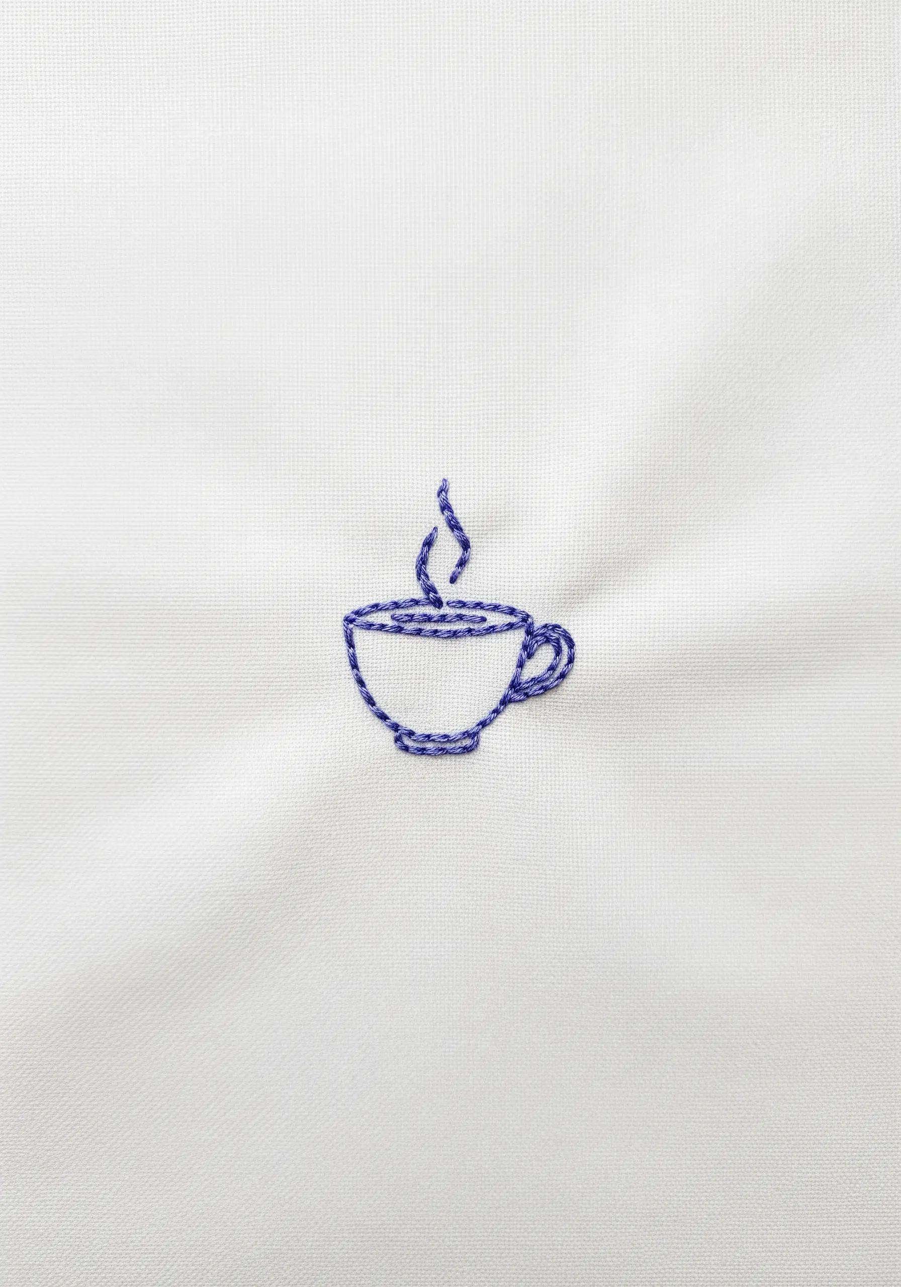 A simple outline of a coffee cup stitched with blue variegated thread.