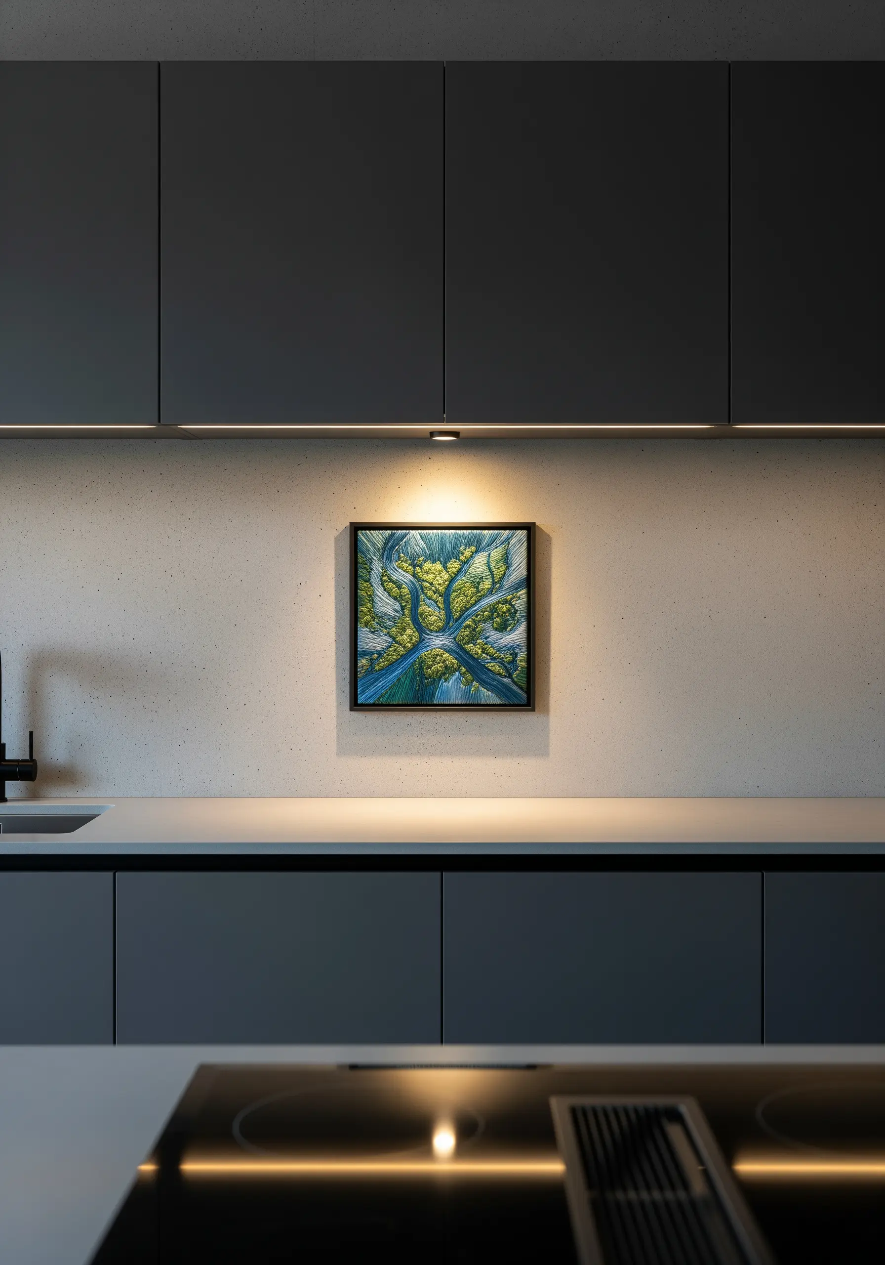 A single, intricately embroidered aerial landscape in a black frame under cabinet lighting.