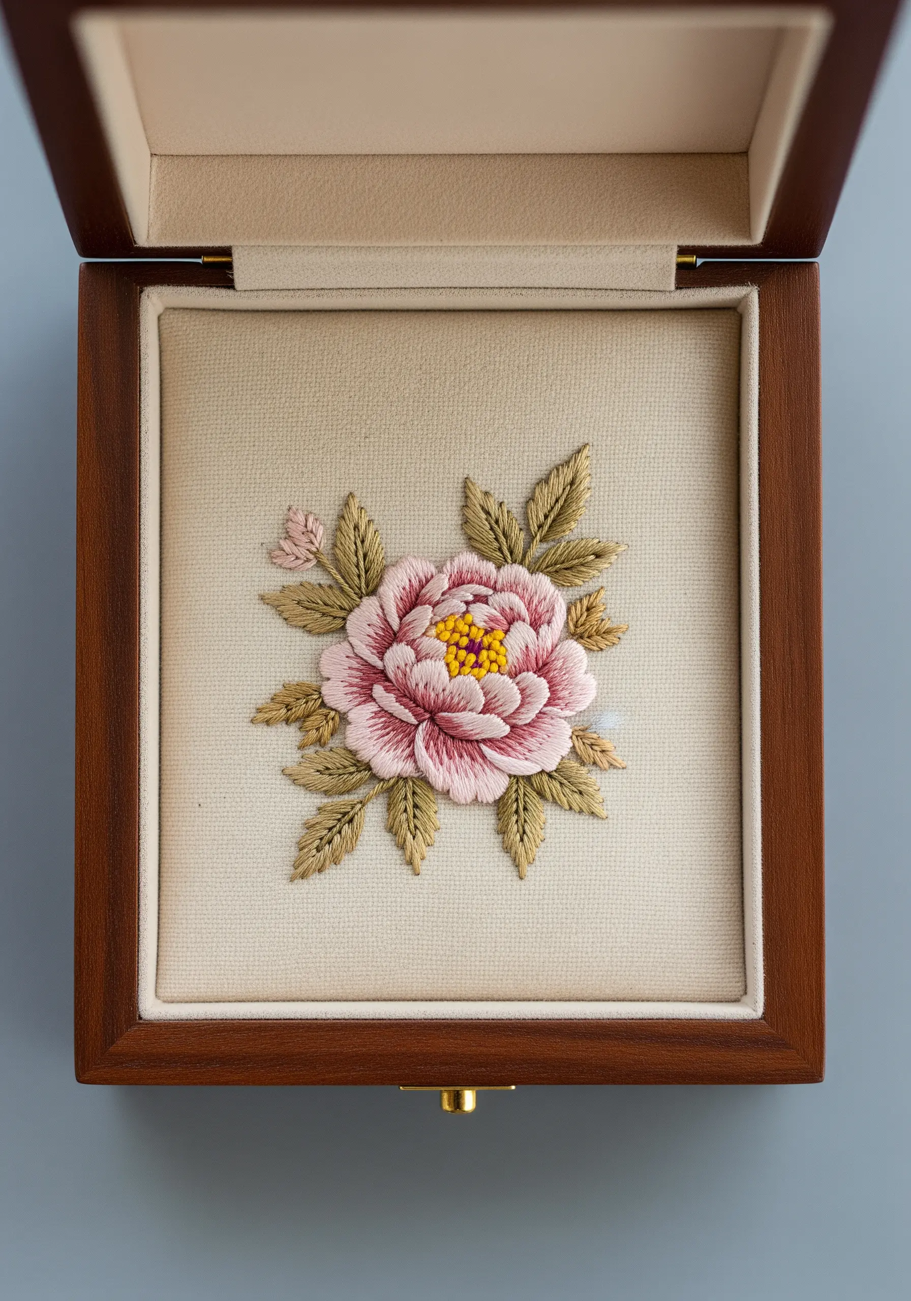 A small pink peony embroidery, padded and mounted inside a wooden jewelry box.