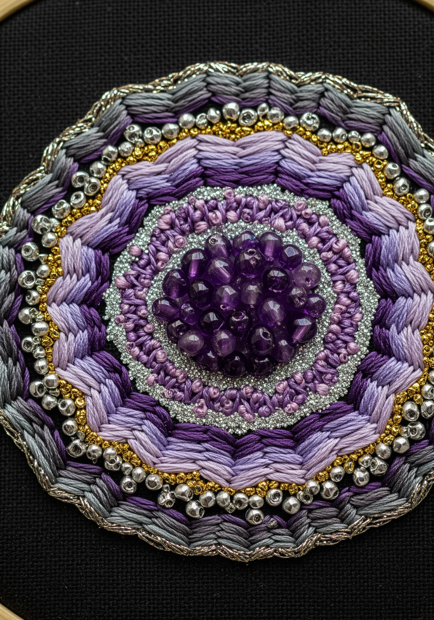 Intricate geode embroidery with purple gradients, beads, and metallic thread on black fabric.