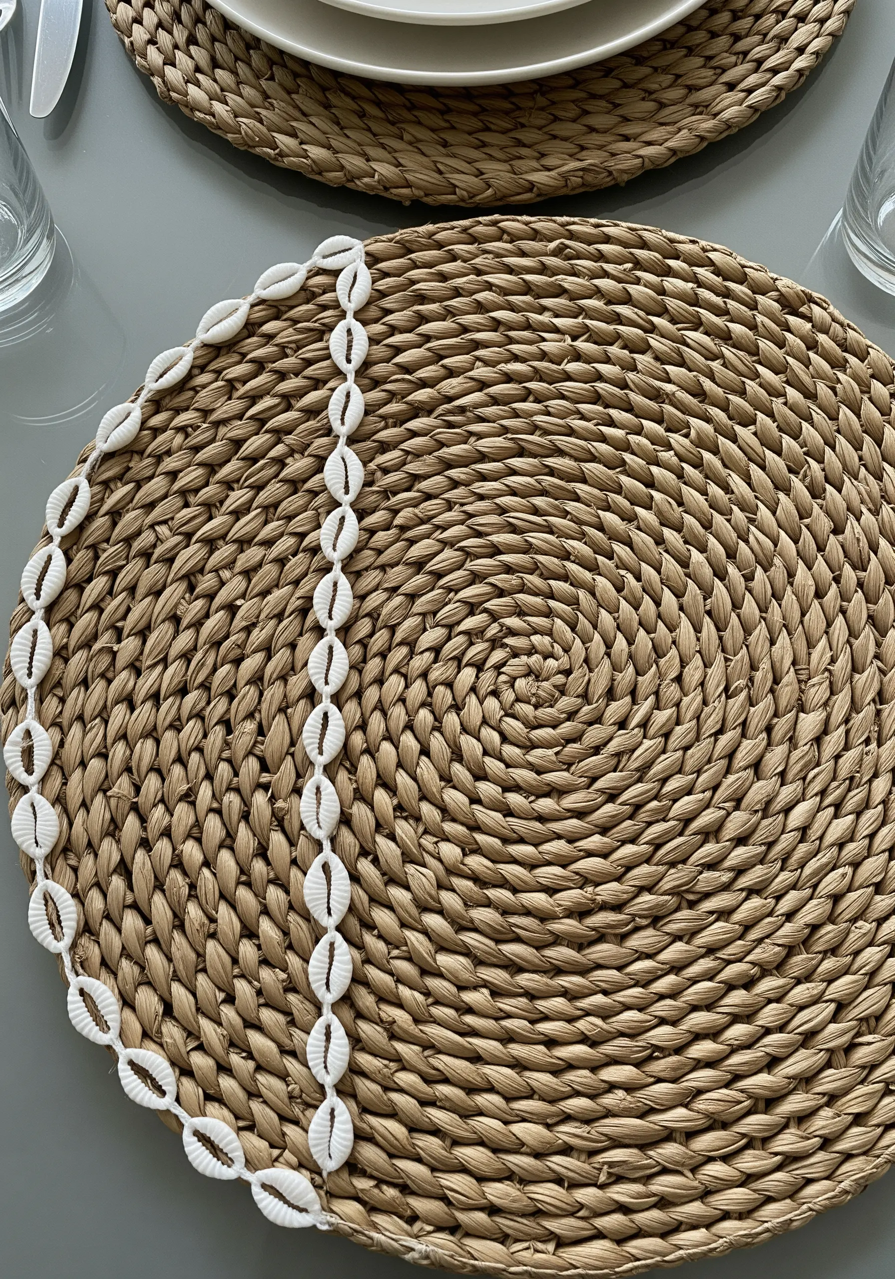 A woven placemat with a line of real cowrie shells stitched along one edge.