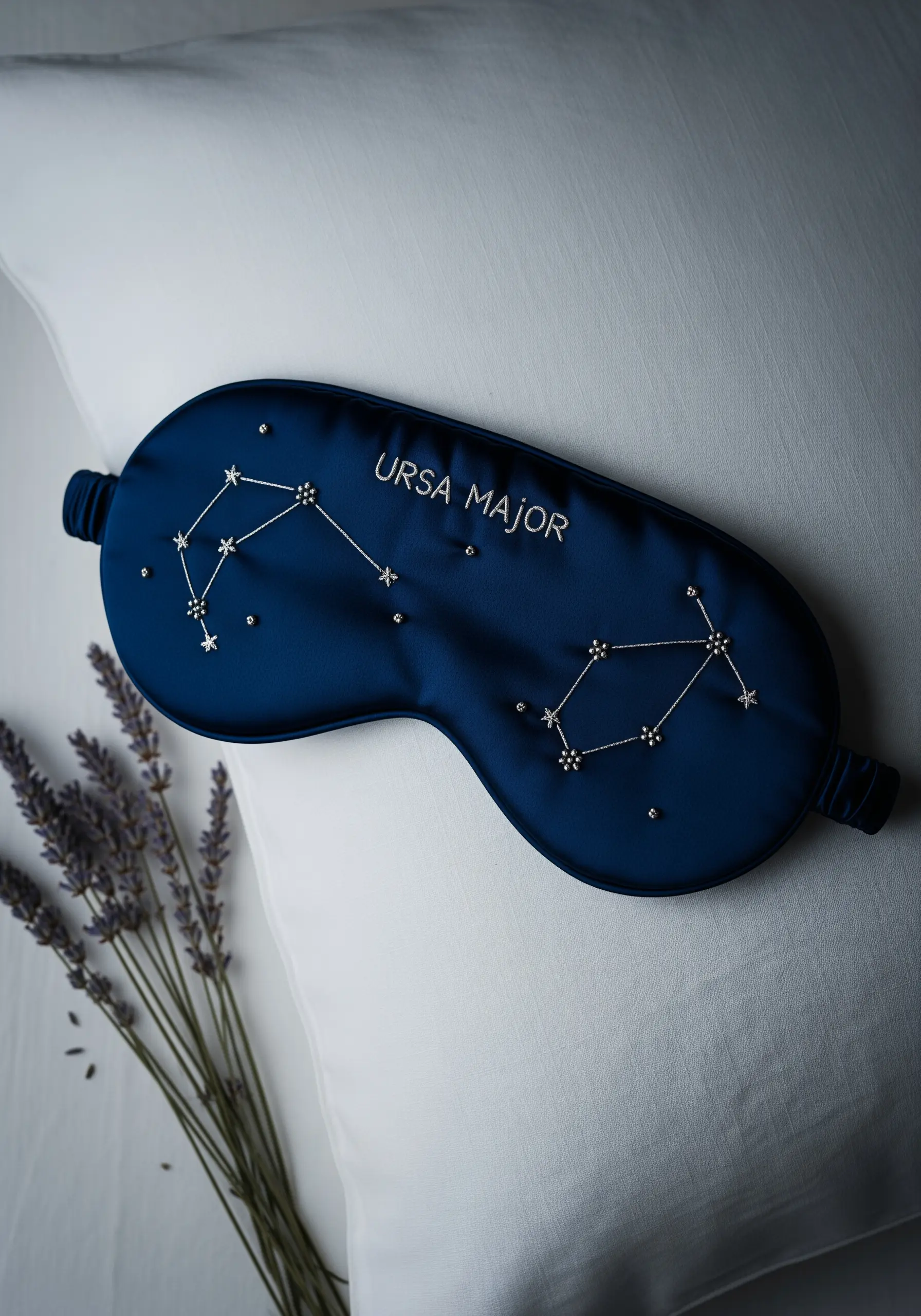 A navy blue silk sleep mask embroidered with the Ursa Major constellation using silver thread and beads.
