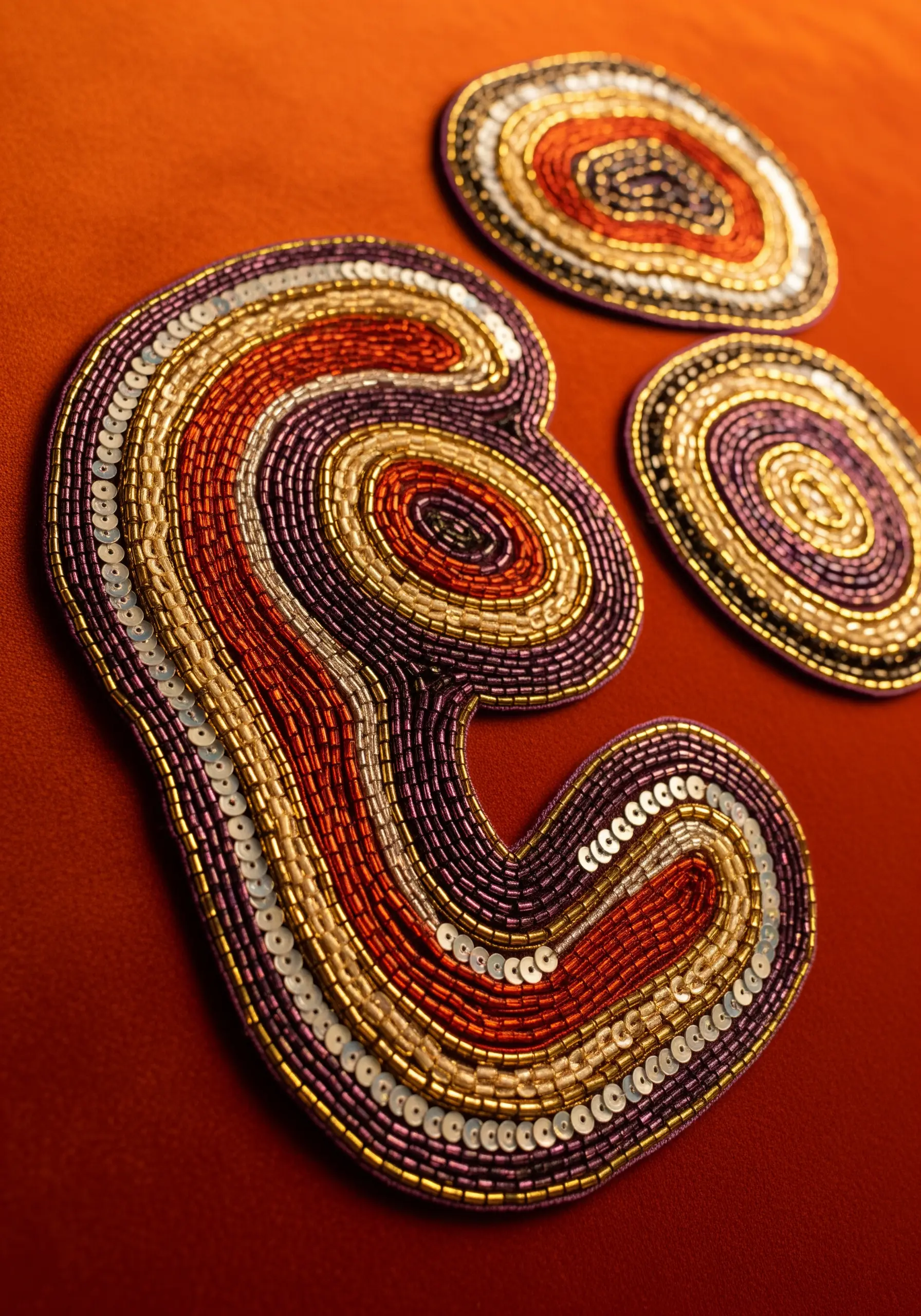 Abstract organic shapes outlined with rows of metallic beads and sequins.