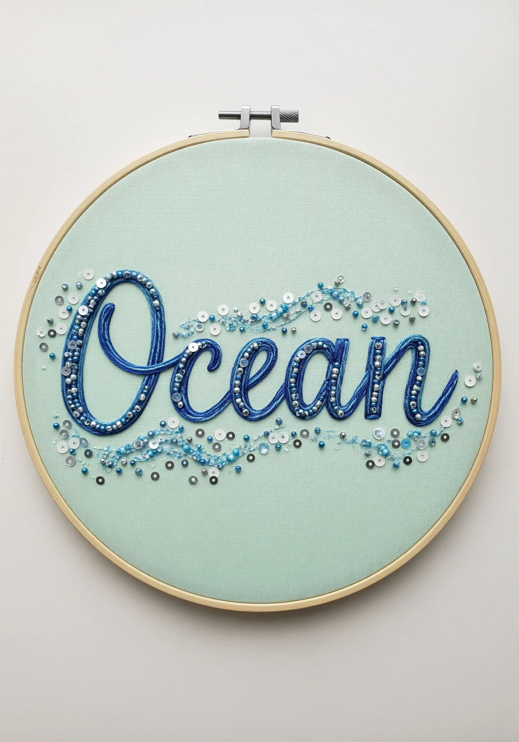 The word 'Ocean' embroidered in blue and embellished with a scatter of beads and sequins.