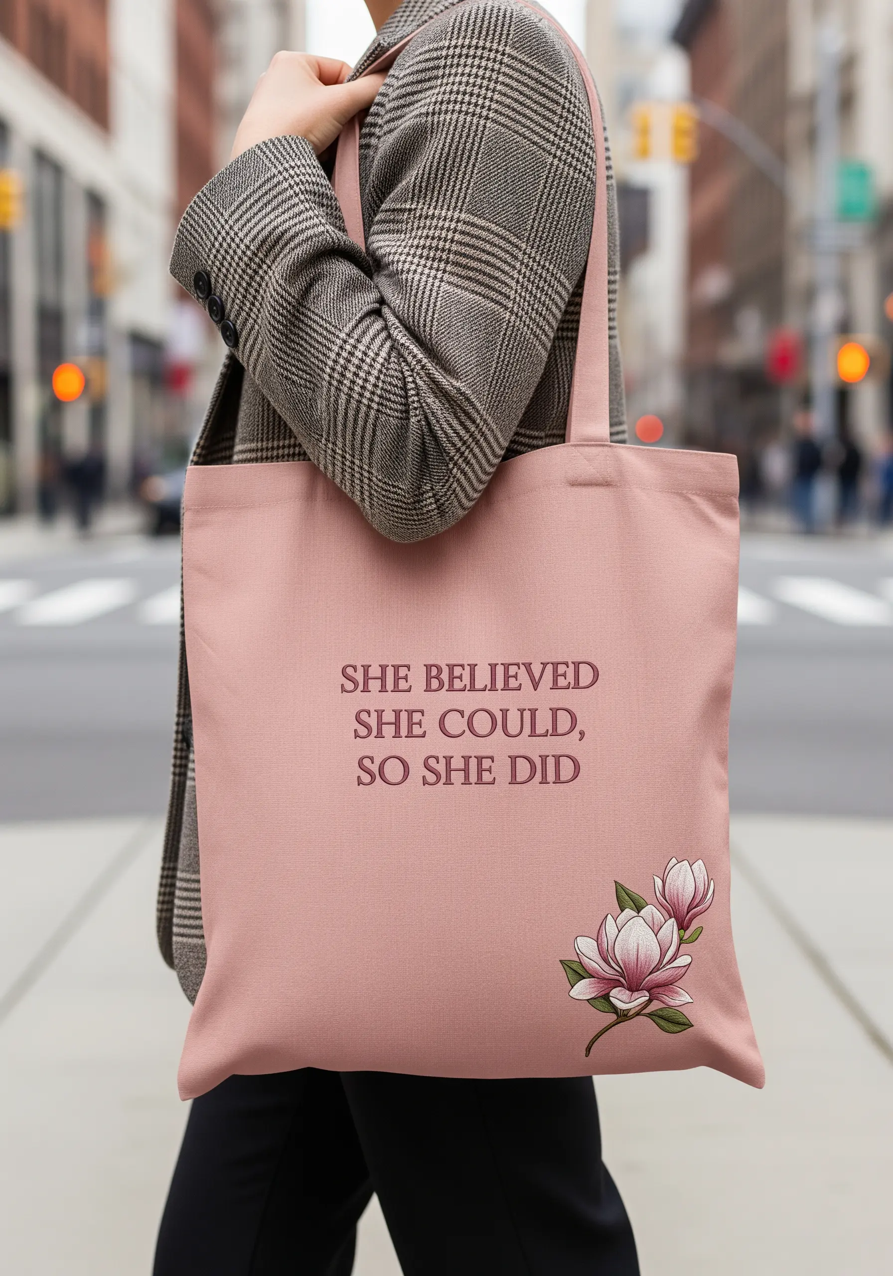 Embroidered quote on a pink tote bag with a small, detailed magnolia flower in the corner.