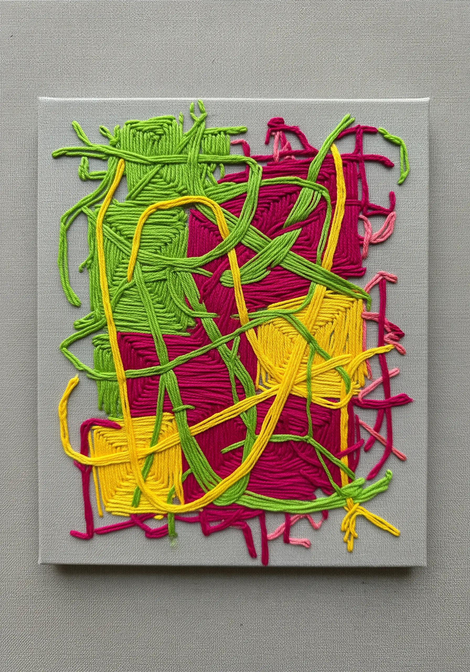 Abstract embroidery on canvas using thick, couched yarns in green, yellow, and magenta.