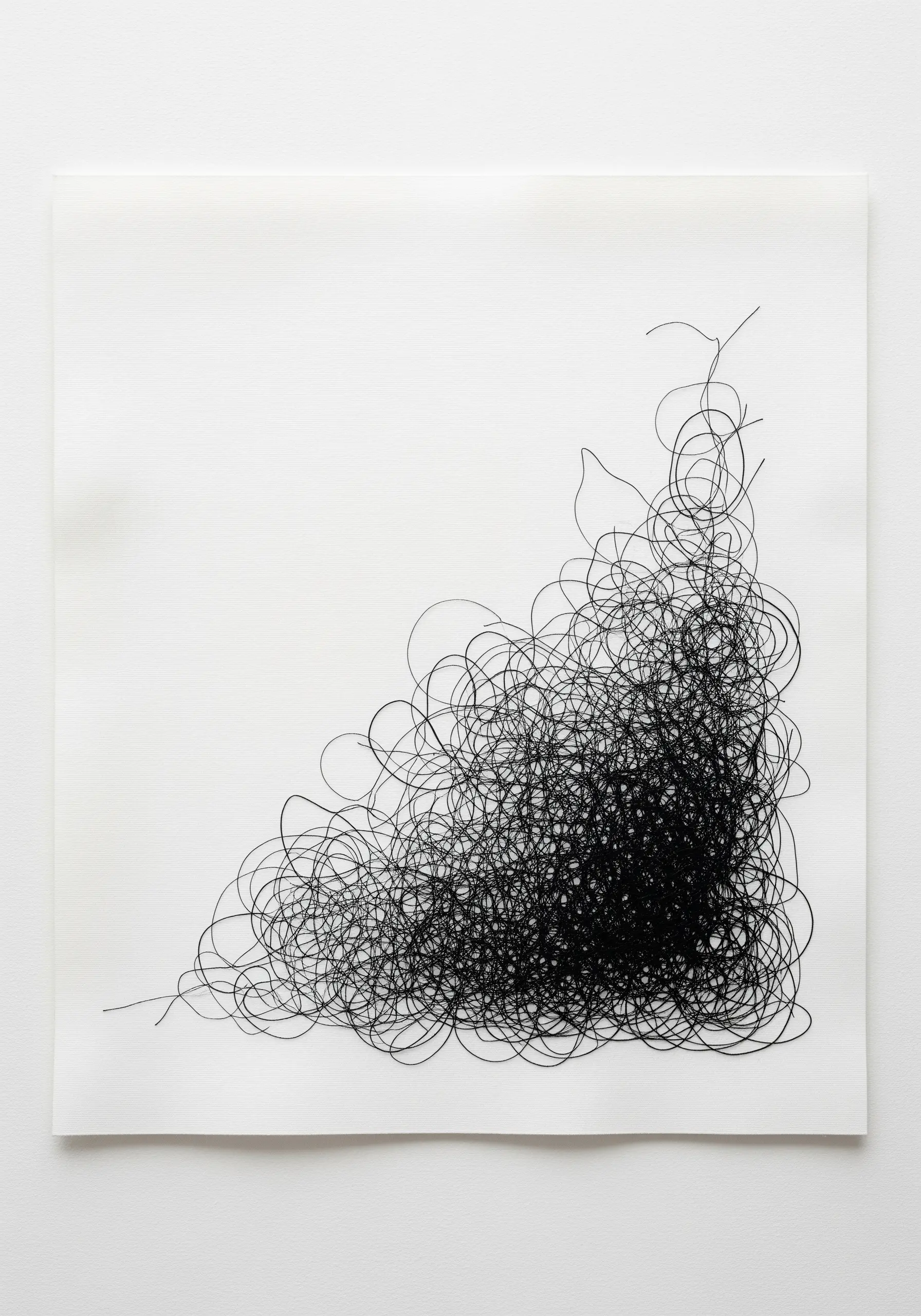 A dense, chaotic scribble of black thread concentrated in the corner of a white canvas.