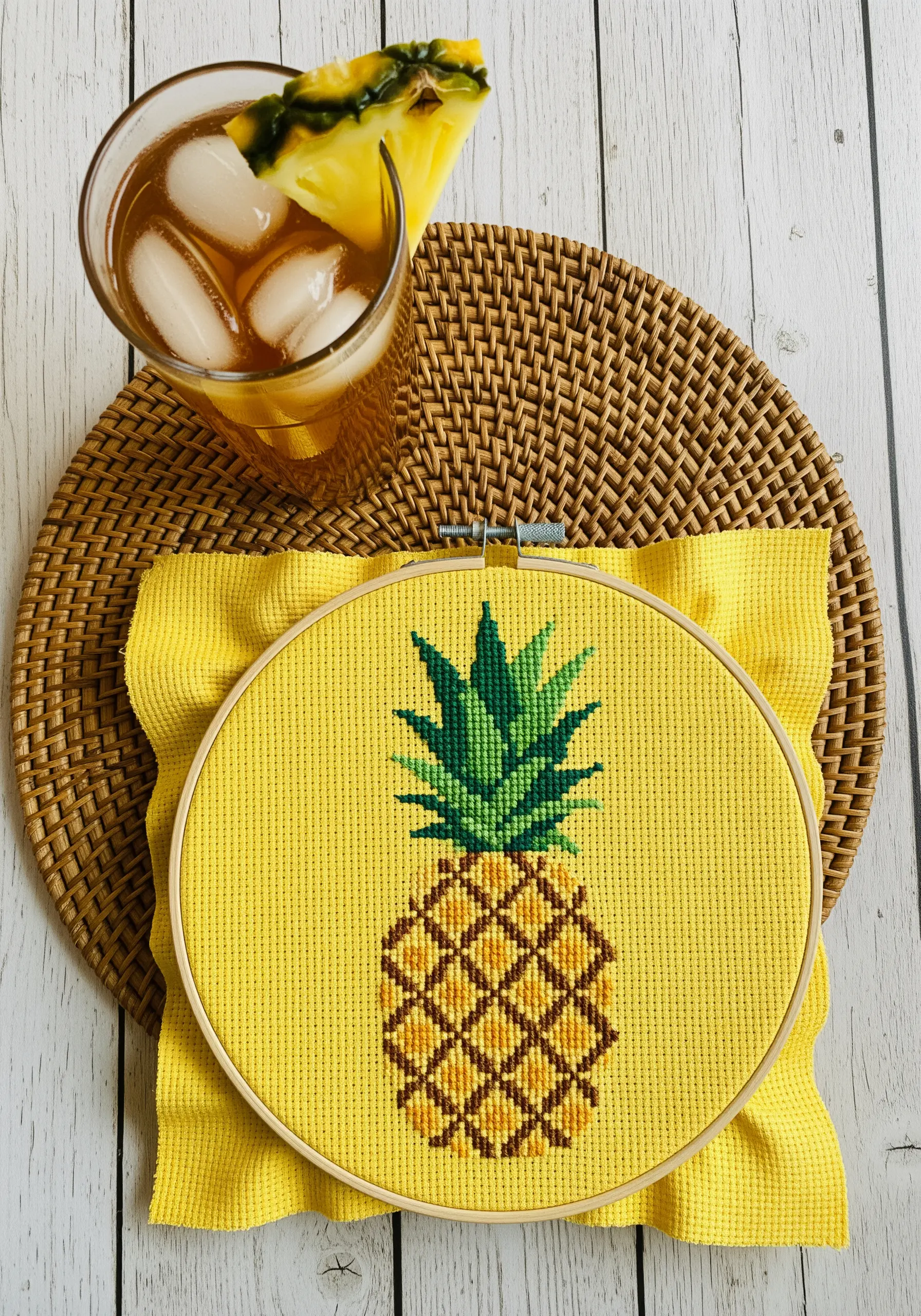 Cross-stitched pineapple with a geometric pattern on bright yellow Aida cloth.